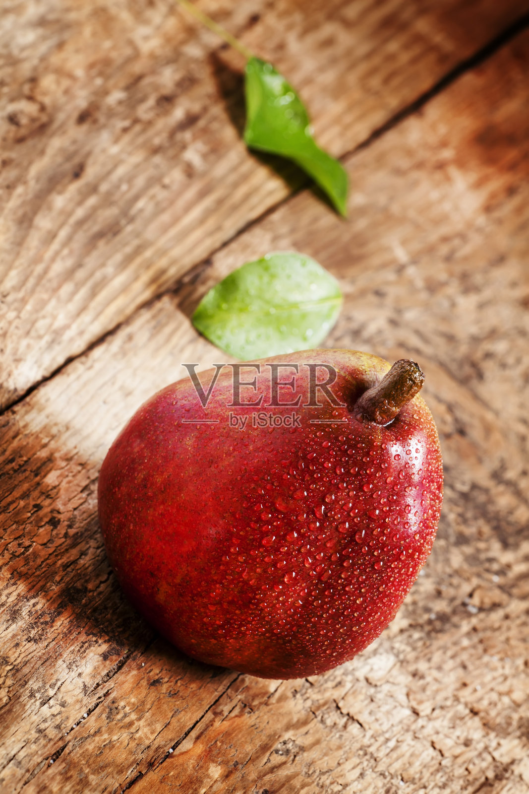 鲜红的梨子和水滴放在木桌上照片摄影图片