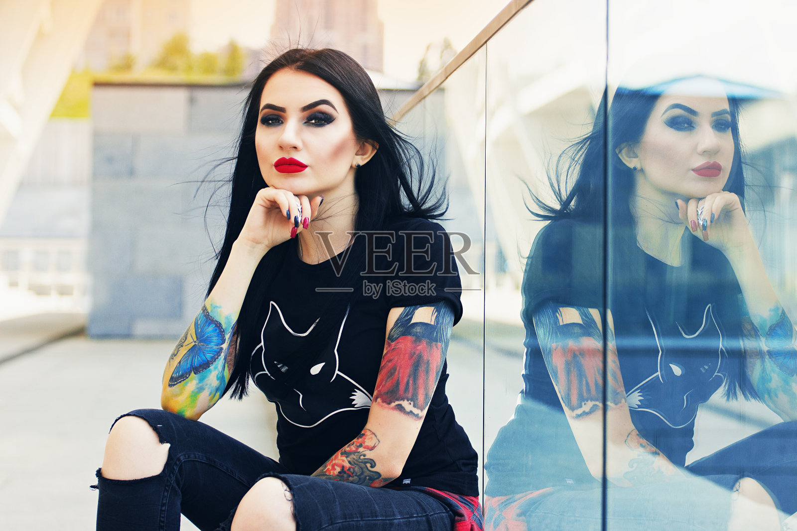 西塞的美丽。肖像美丽的纹身潮女孩摆姿势的相机，而坐在城市的背景。照片摄影图片