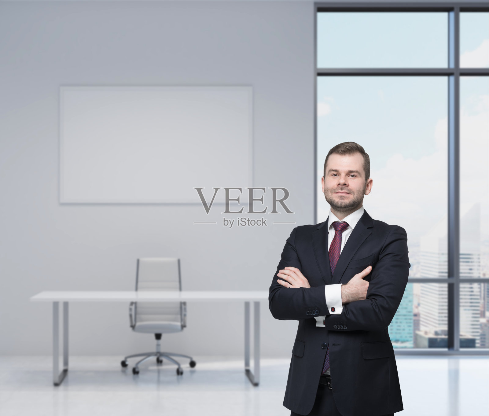 微笑英俊的商人穿着黑色西装，双臂交叉。照片摄影图片