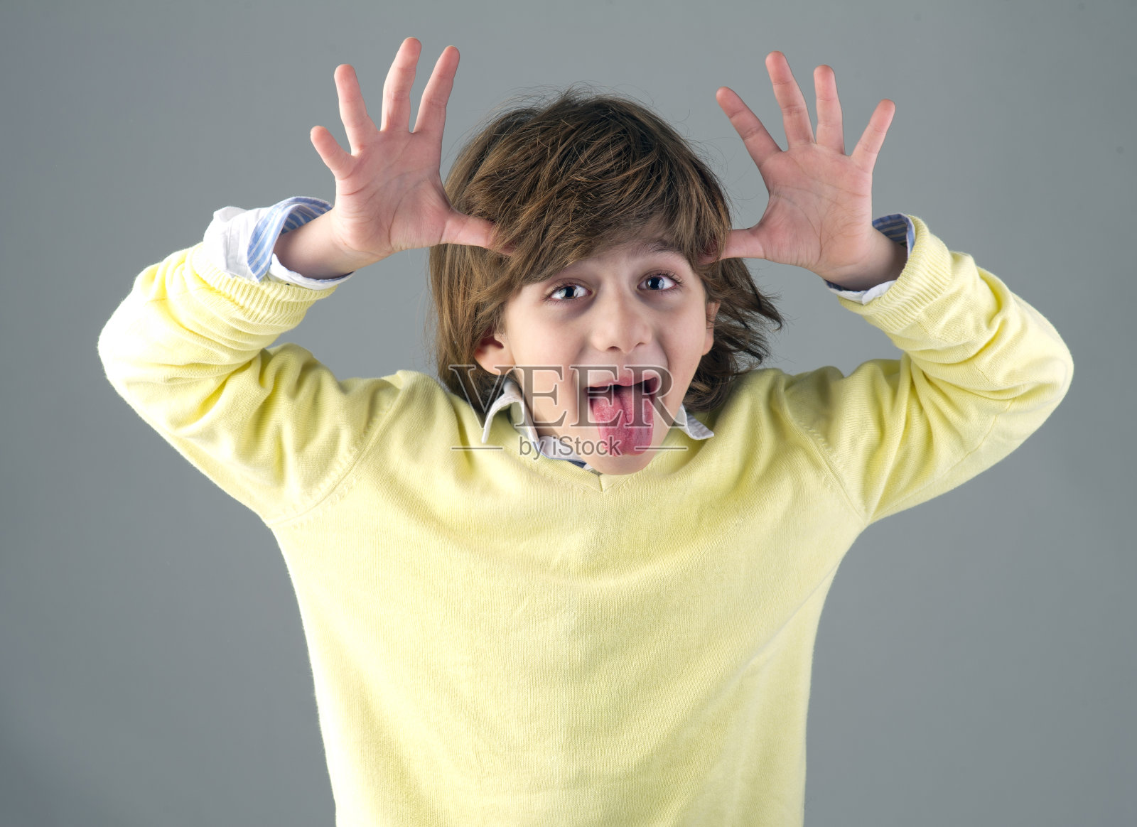 聪明漂亮的孩子做傻傻的脸孤立在灰色照片摄影图片