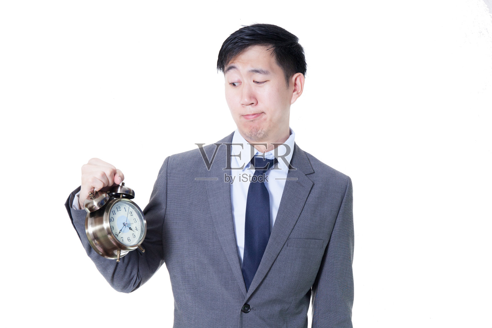 年轻的亚洲商人拿着一个时钟在不愉快的脸表情照片摄影图片