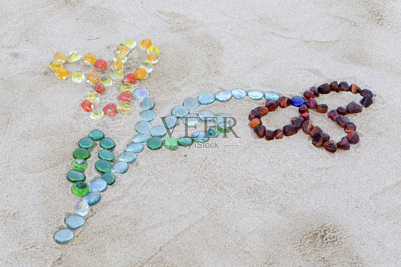 花形纹理的沙滩上有五颜六色的鹅卵石照片摄影图片