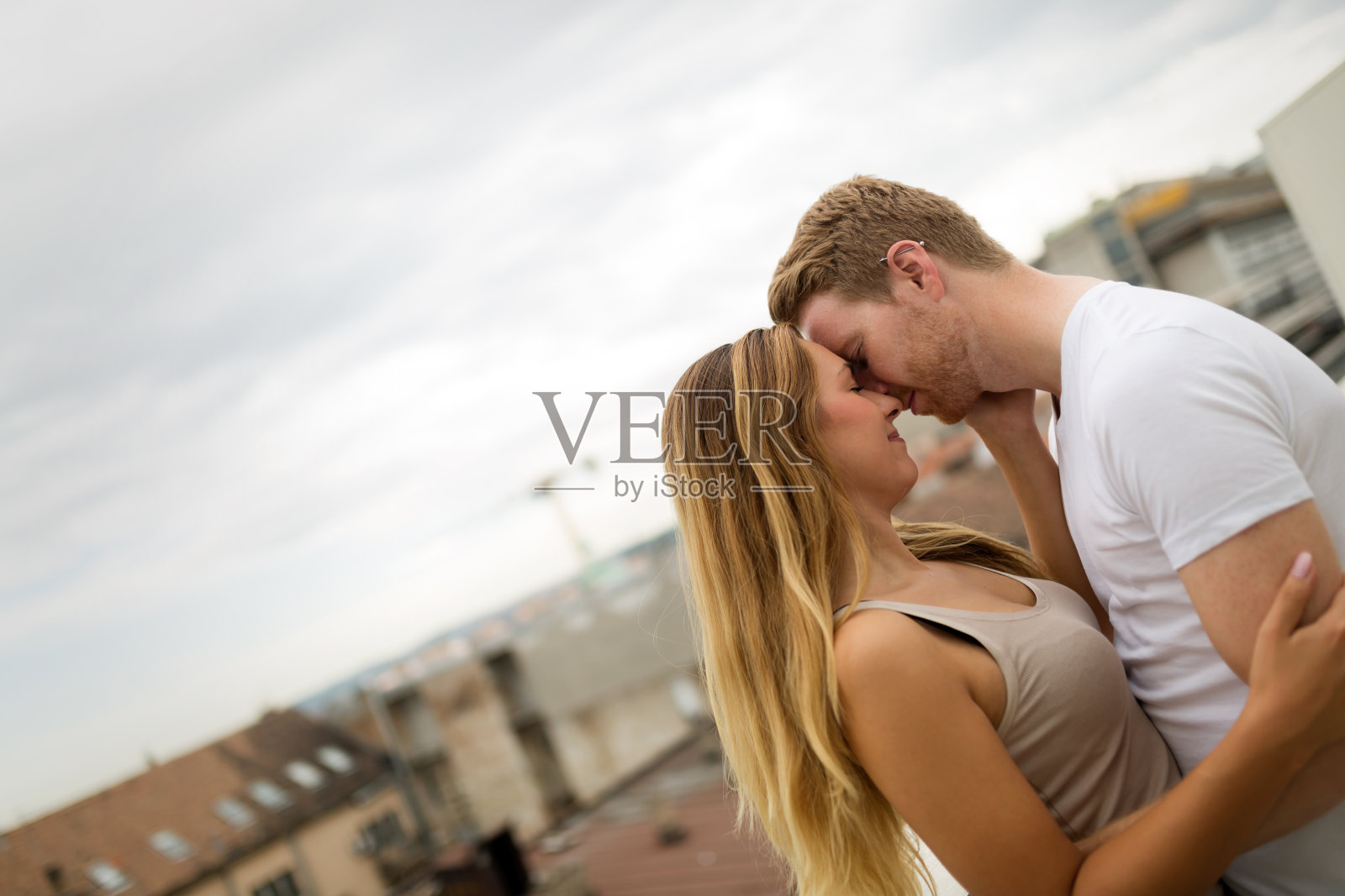一对相爱的情侣在屋顶上接吻照片摄影图片