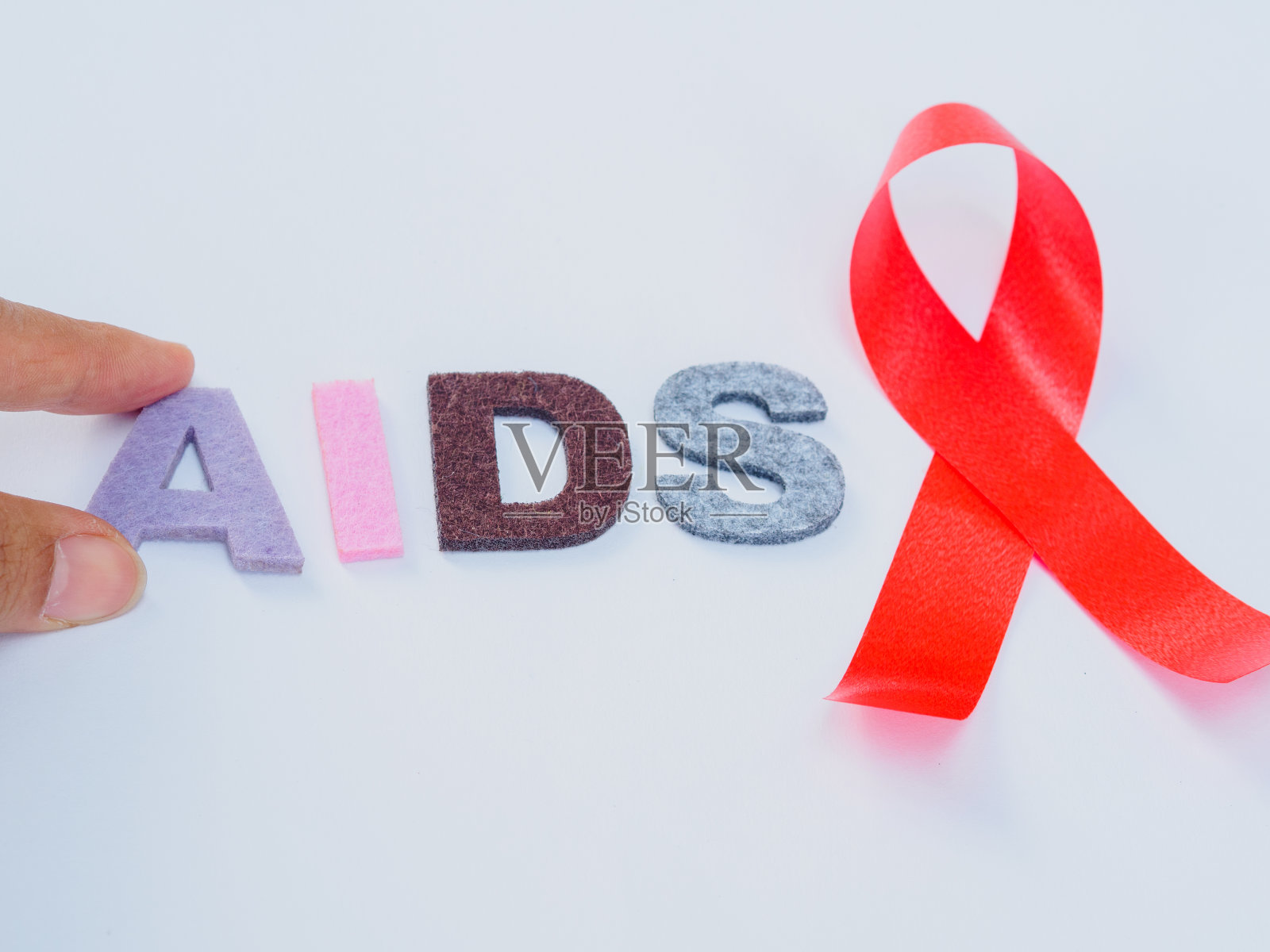 世界艾滋病日的概念。红丝带与手牵手艾滋病文字照片摄影图片
