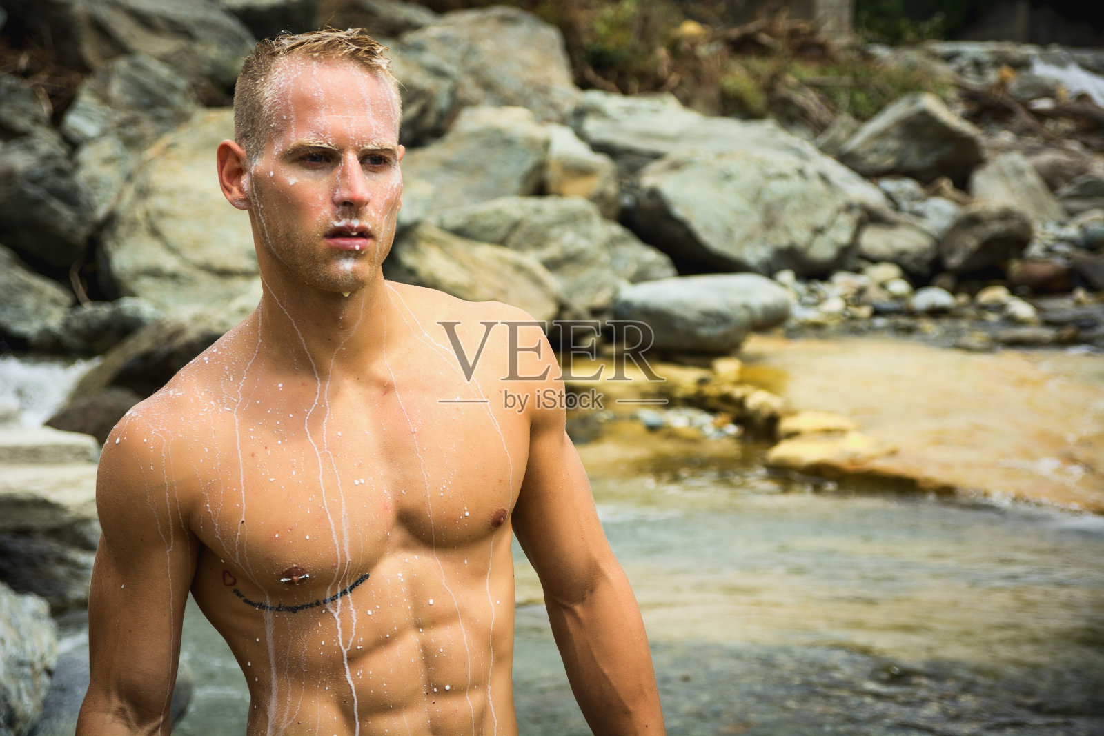 英俊的年轻肌肉男子站在池塘里照片摄影图片