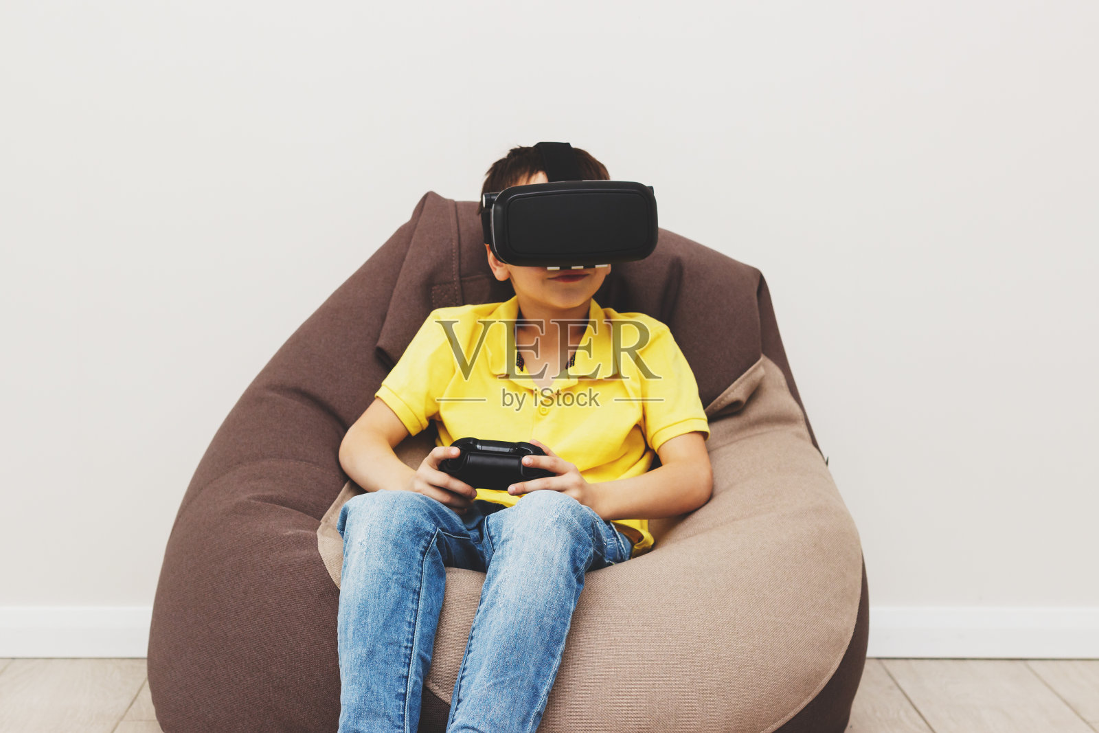 男孩戴着虚拟现实眼镜在室内玩游戏照片摄影图片