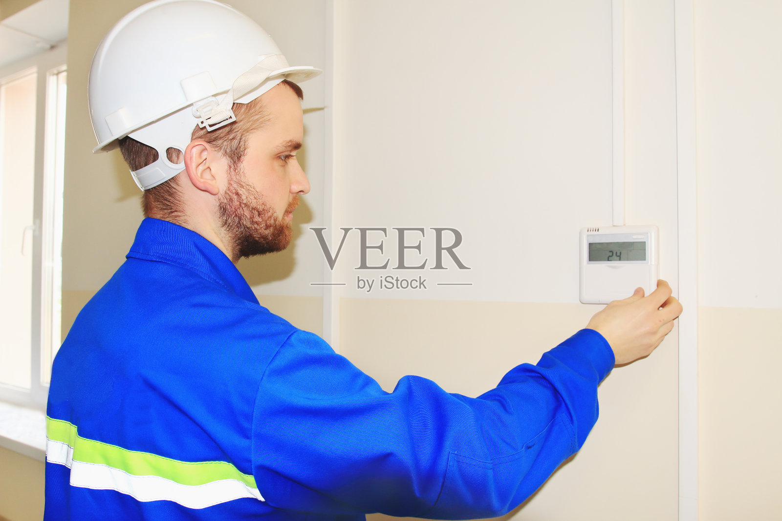 白盔工程师通过空调控制面板设置温度照片摄影图片