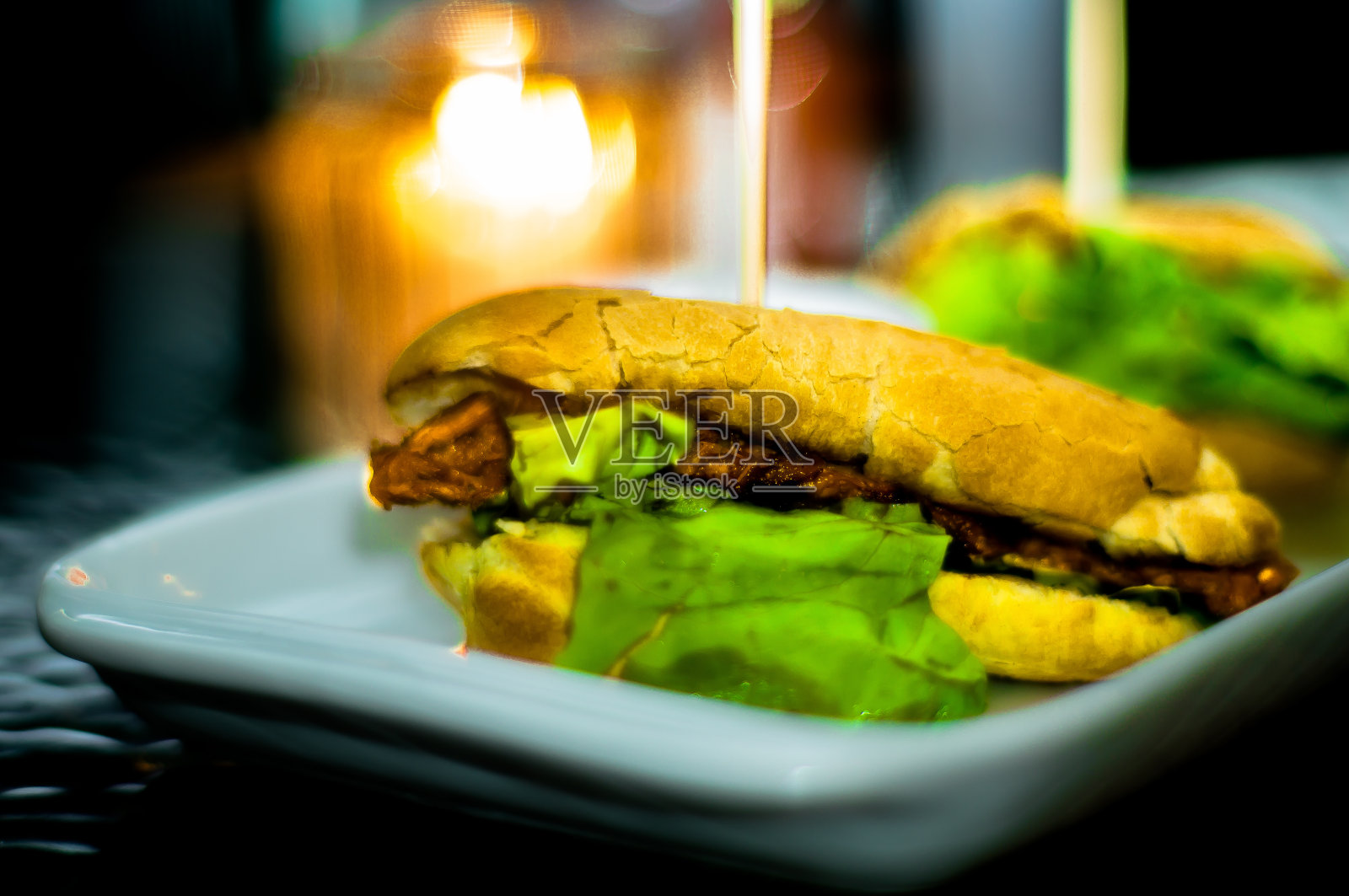 白盘子上夹着法式长棍面包和生菜，背景模糊，选择性聚焦，光线柔和照片摄影图片