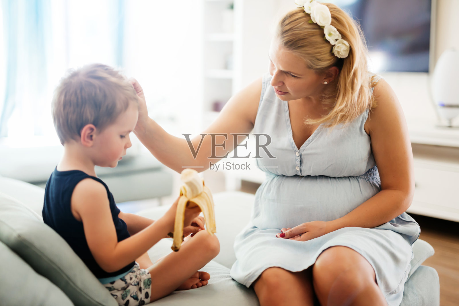 美丽的孕妇照顾儿子，分享香蕉照片摄影图片