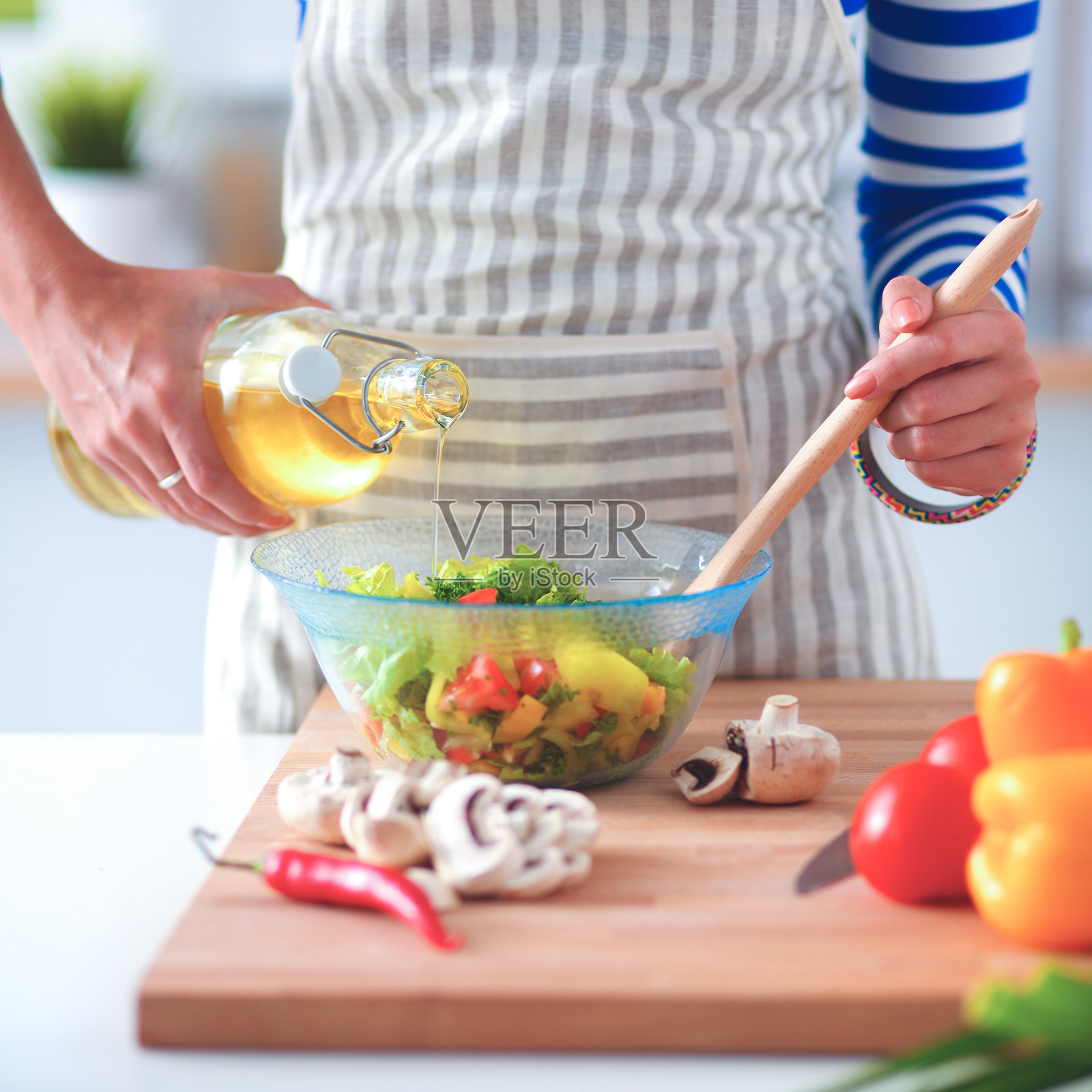 一个年轻女子站在桌前拌新鲜沙拉照片摄影图片