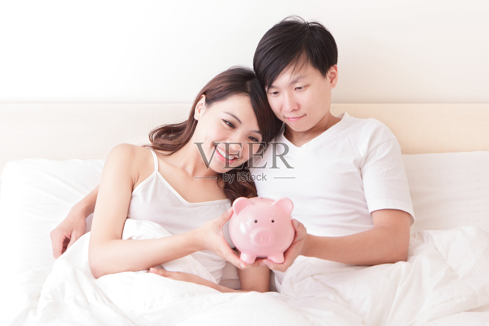 幸福的夫妇和粉红色的存钱罐照片摄影图片