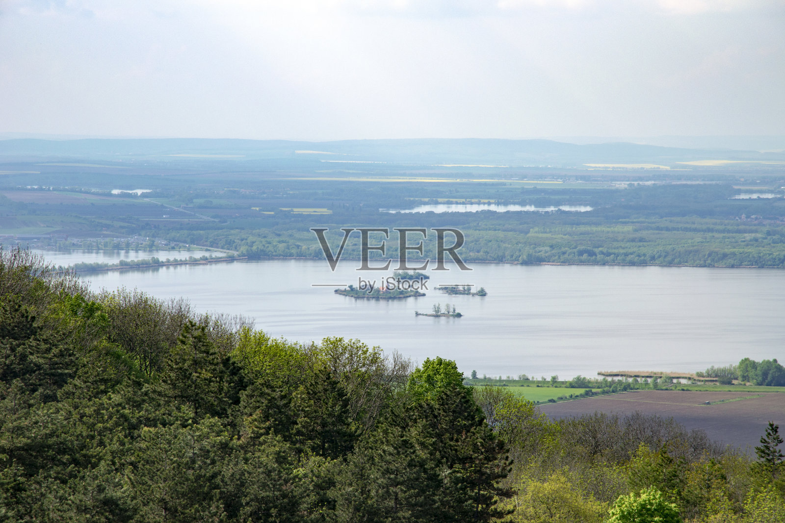 看丘陵景观Pálava与森林，岩石和湖Nové Mlýny在南摩拉维亚天空下与云在雨照片摄影图片