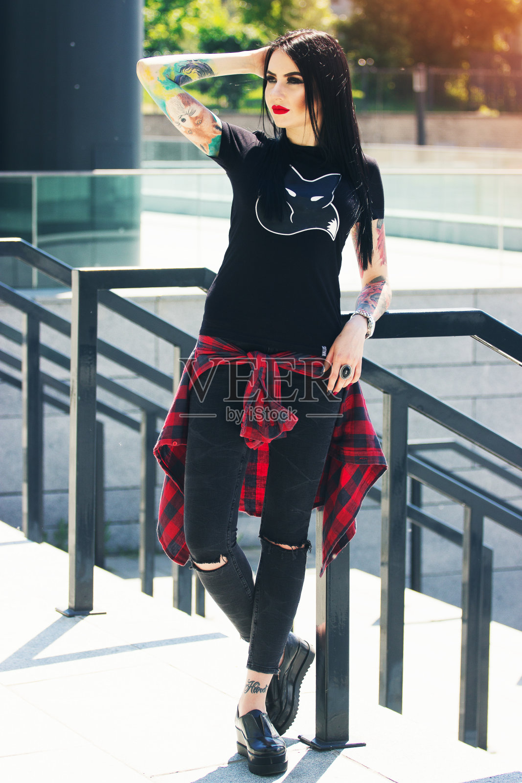 美丽的纹身。肖像的年轻美丽的纹身潮女孩摆姿势的相机，而站在城市的背景。照片摄影图片