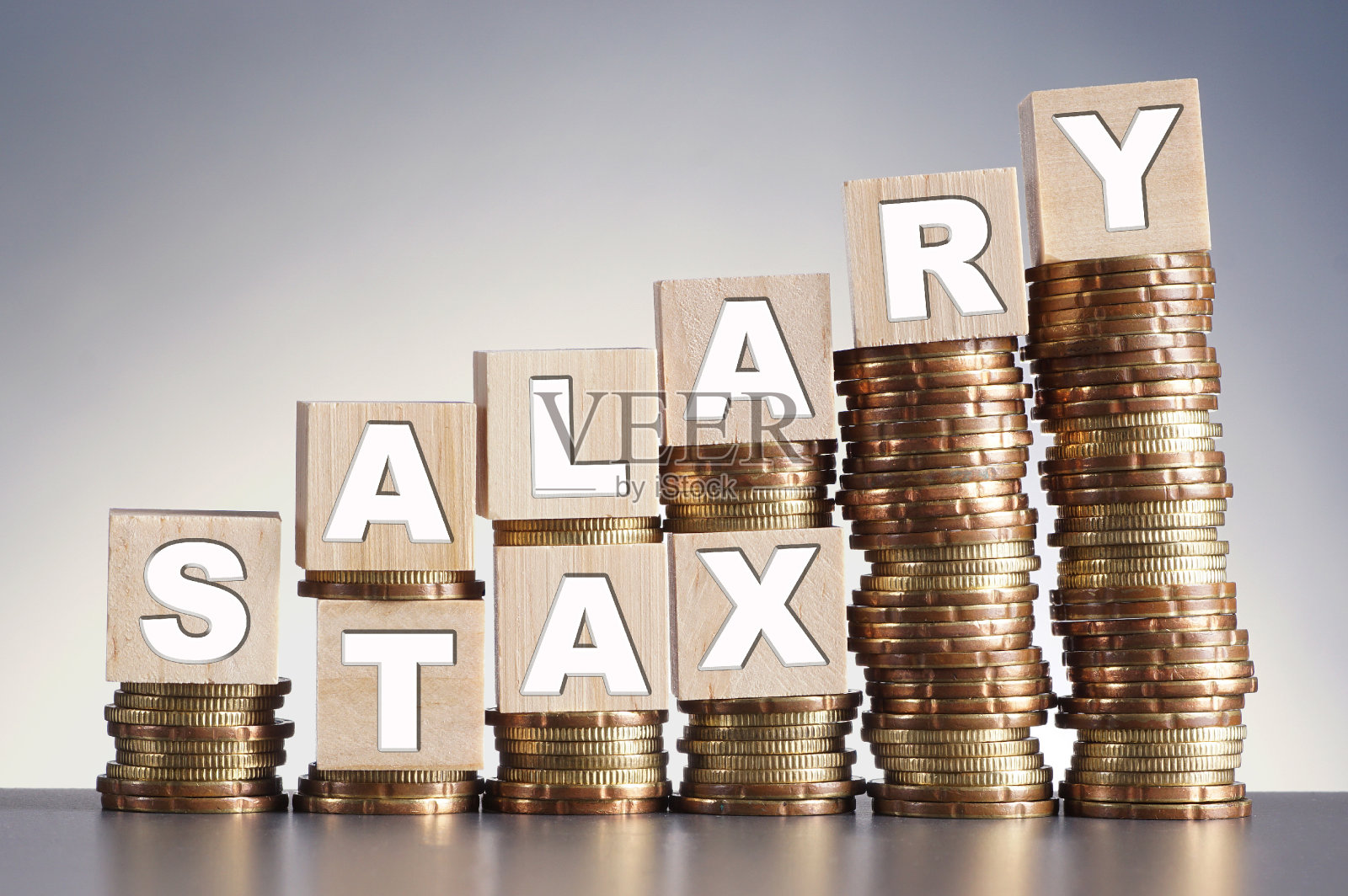 “工资”和“税”字在增加硬币堆叠梯度背景照片摄影图片