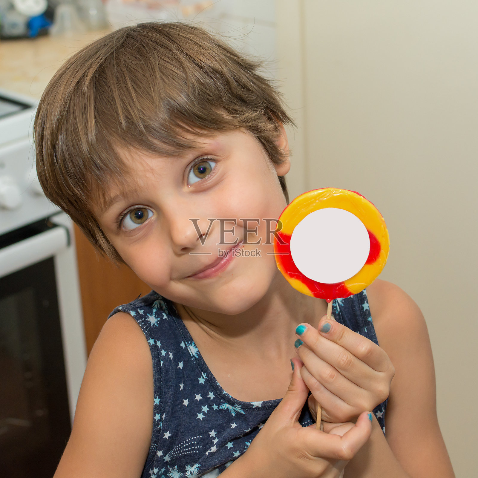 小女孩在厨房微笑着，吃着棒棒糖照片摄影图片