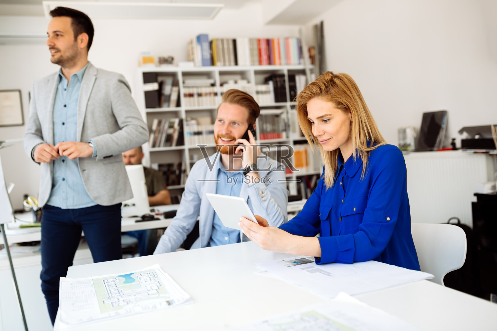 女商人在繁忙的办公室工作，周围有同事照片摄影图片