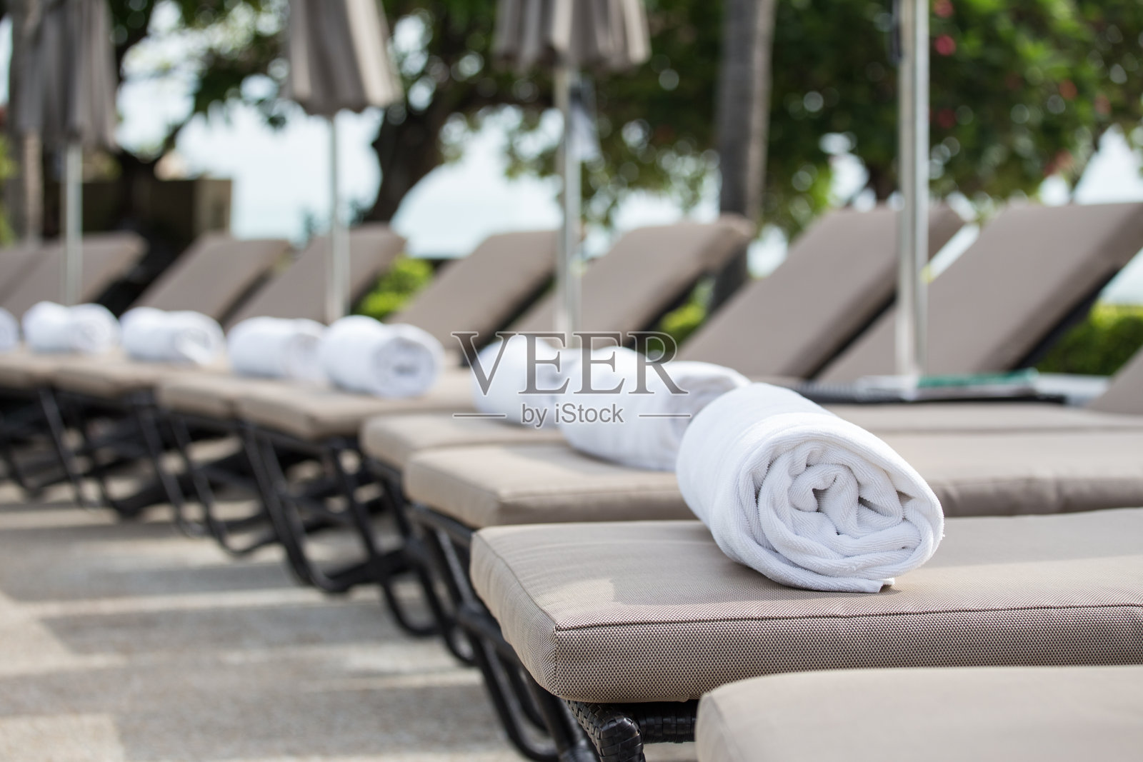 白色毛巾卷在游泳池的日光浴床上有复印空间照片摄影图片