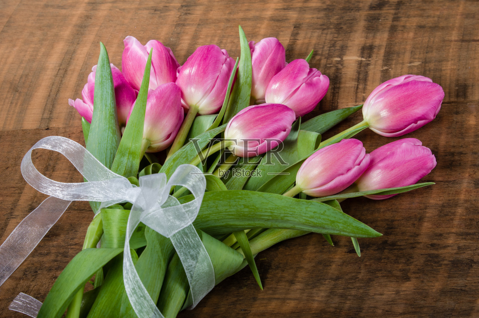 木桌上放着一束粉红色的郁金香照片摄影图片