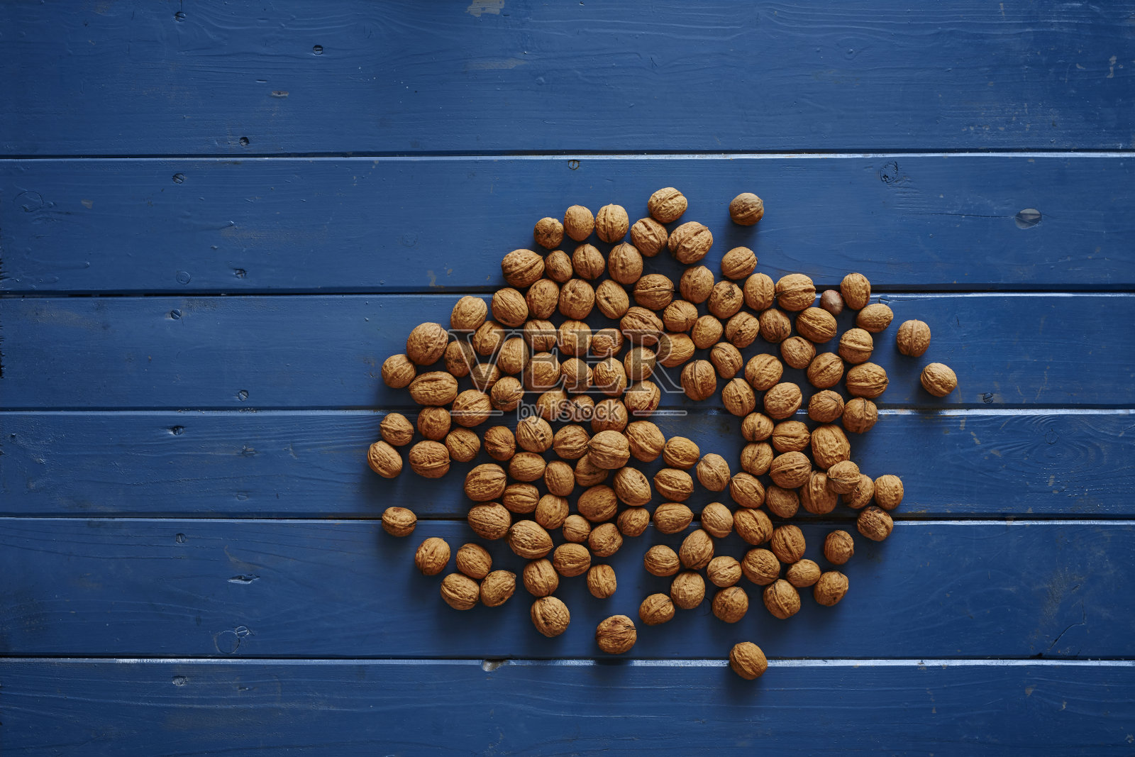 蓝色的木桌上放着一堆核桃照片摄影图片