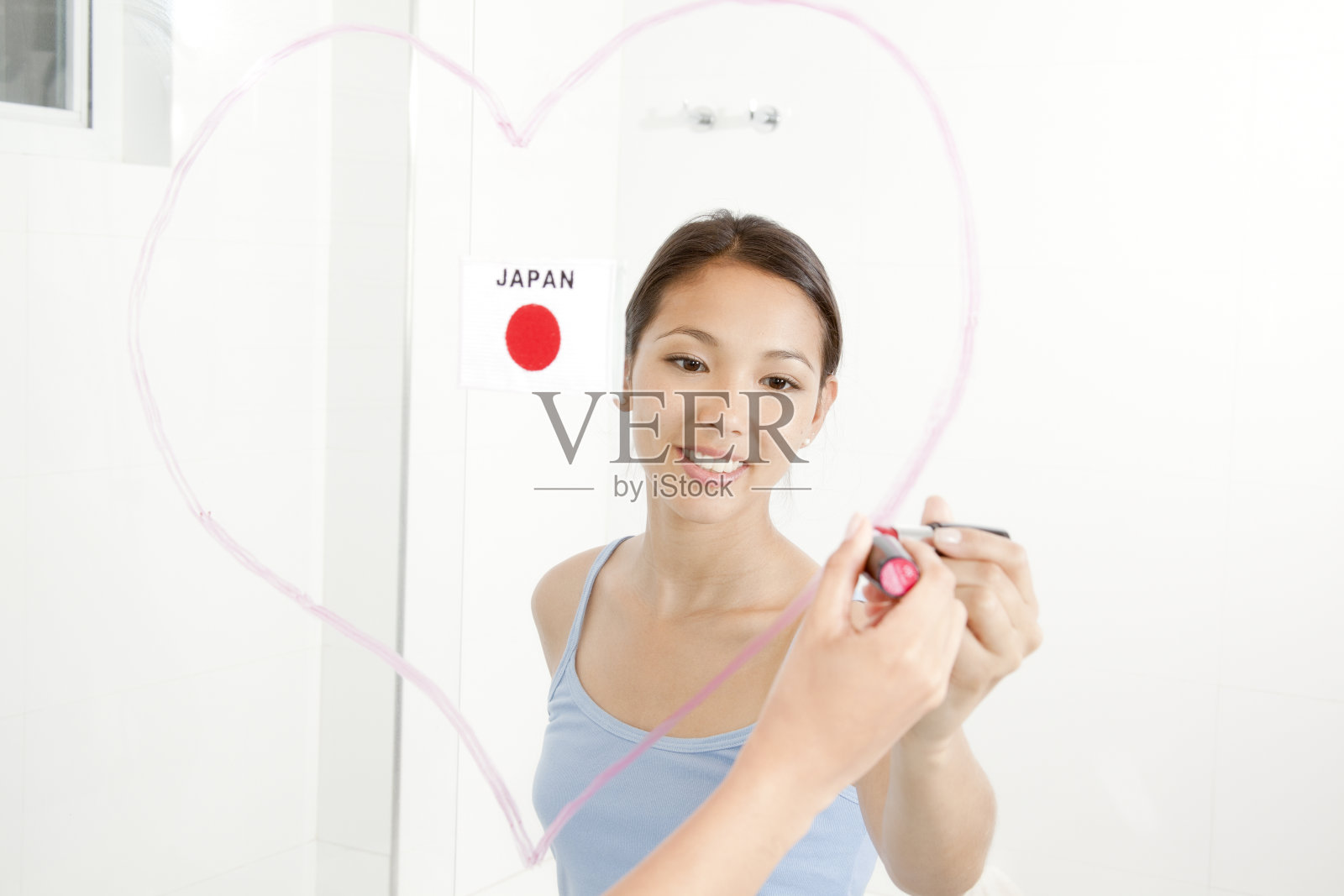 年轻女子用口红在镜子里画了一颗心照片摄影图片