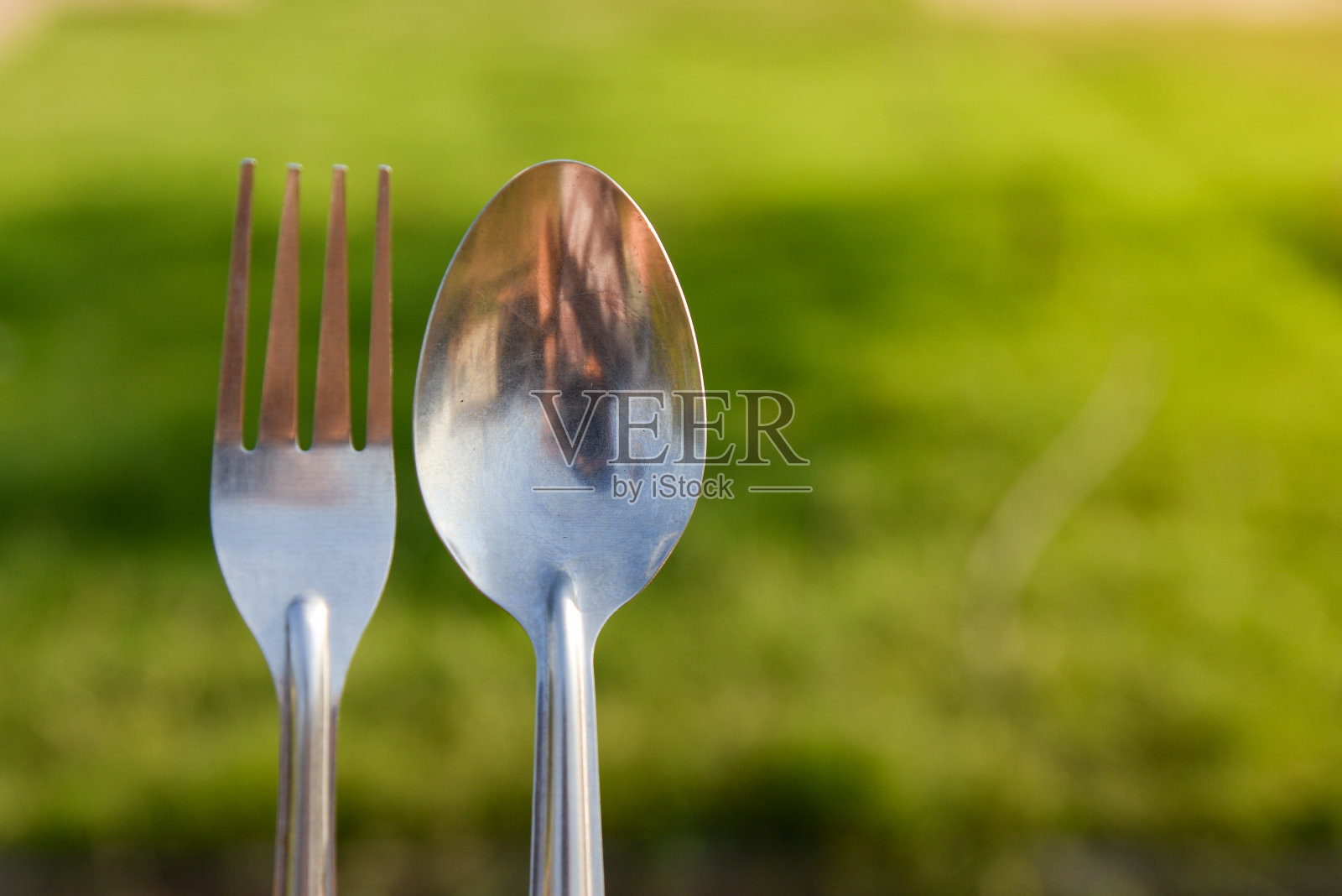 在绿草背景下野餐时用勺子和叉子照片摄影图片