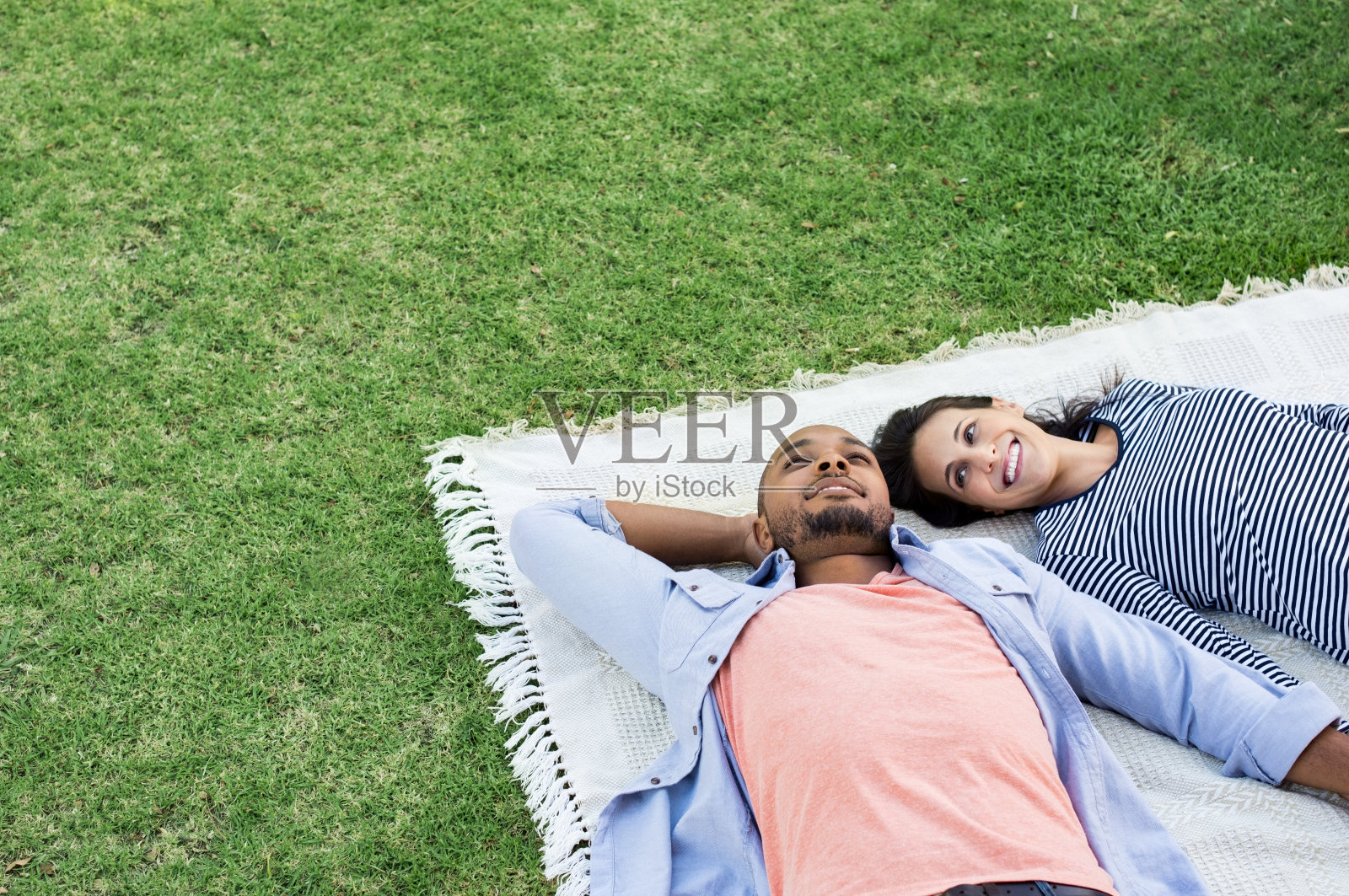 一对夫妇躺在公园的毯子上照片摄影图片