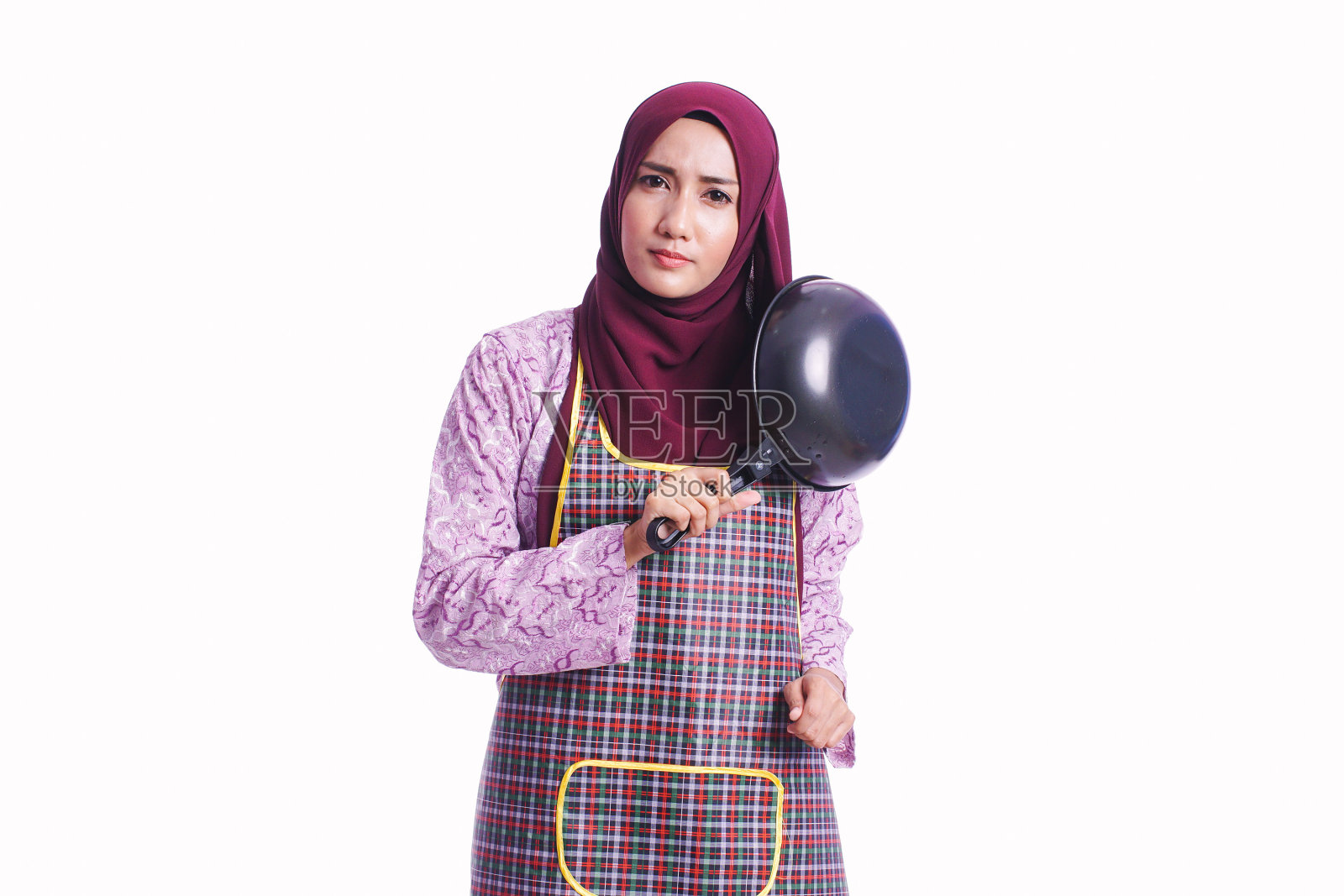 家庭主妇穿着围裙，手持烹饪工具，用不同的肢体语言和面部表情孤立在白色背景上——厨房，家庭和生活方式的概念照片摄影图片