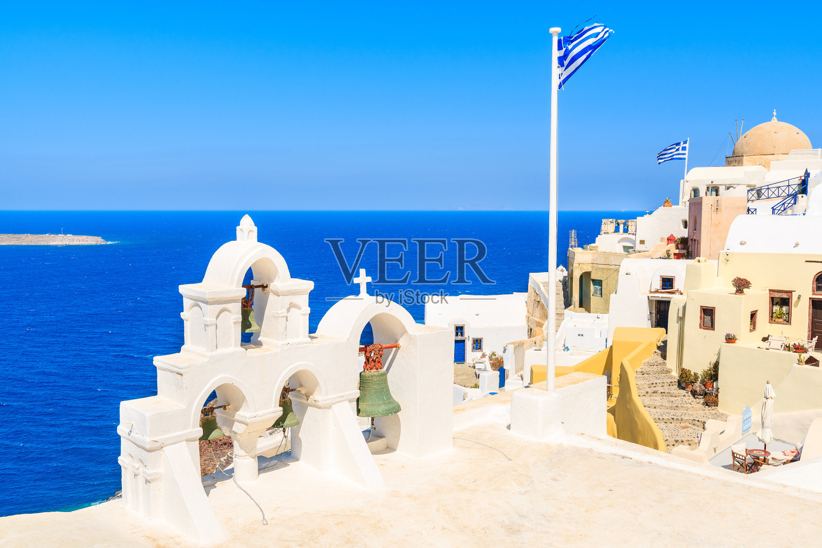希腊圣托里尼岛著名的伊亚村，典型的教堂塔和希腊国旗照片摄影图片