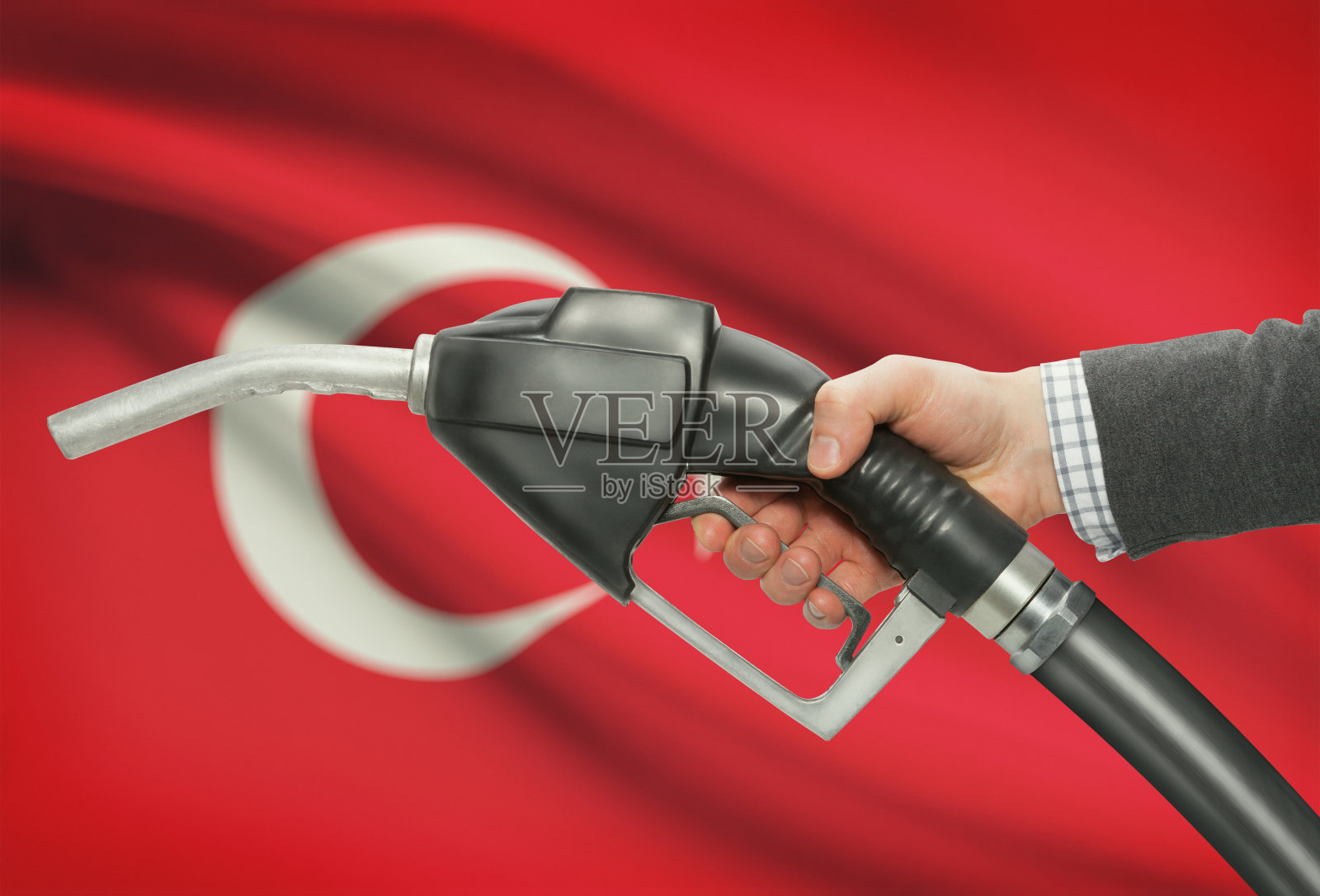 手握燃油泵喷嘴，背景是土耳其国旗照片摄影图片