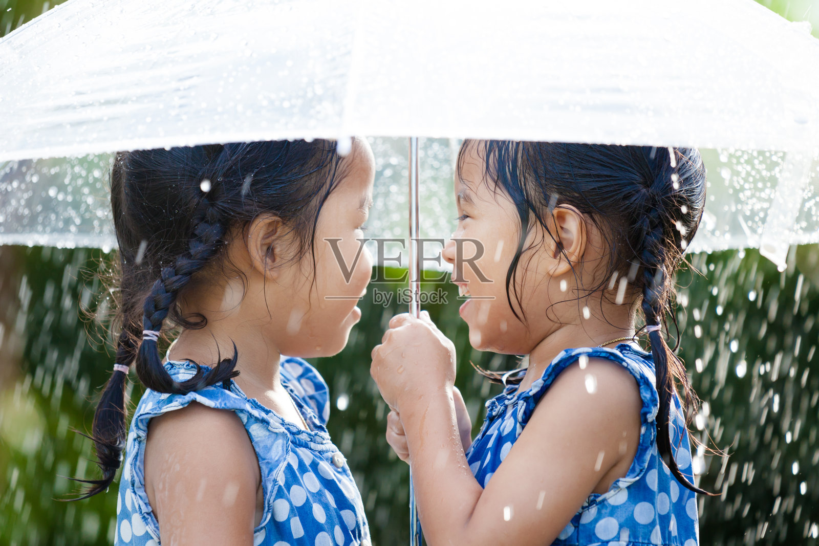 两个快乐的亚洲小女孩带着伞玩雨照片摄影图片