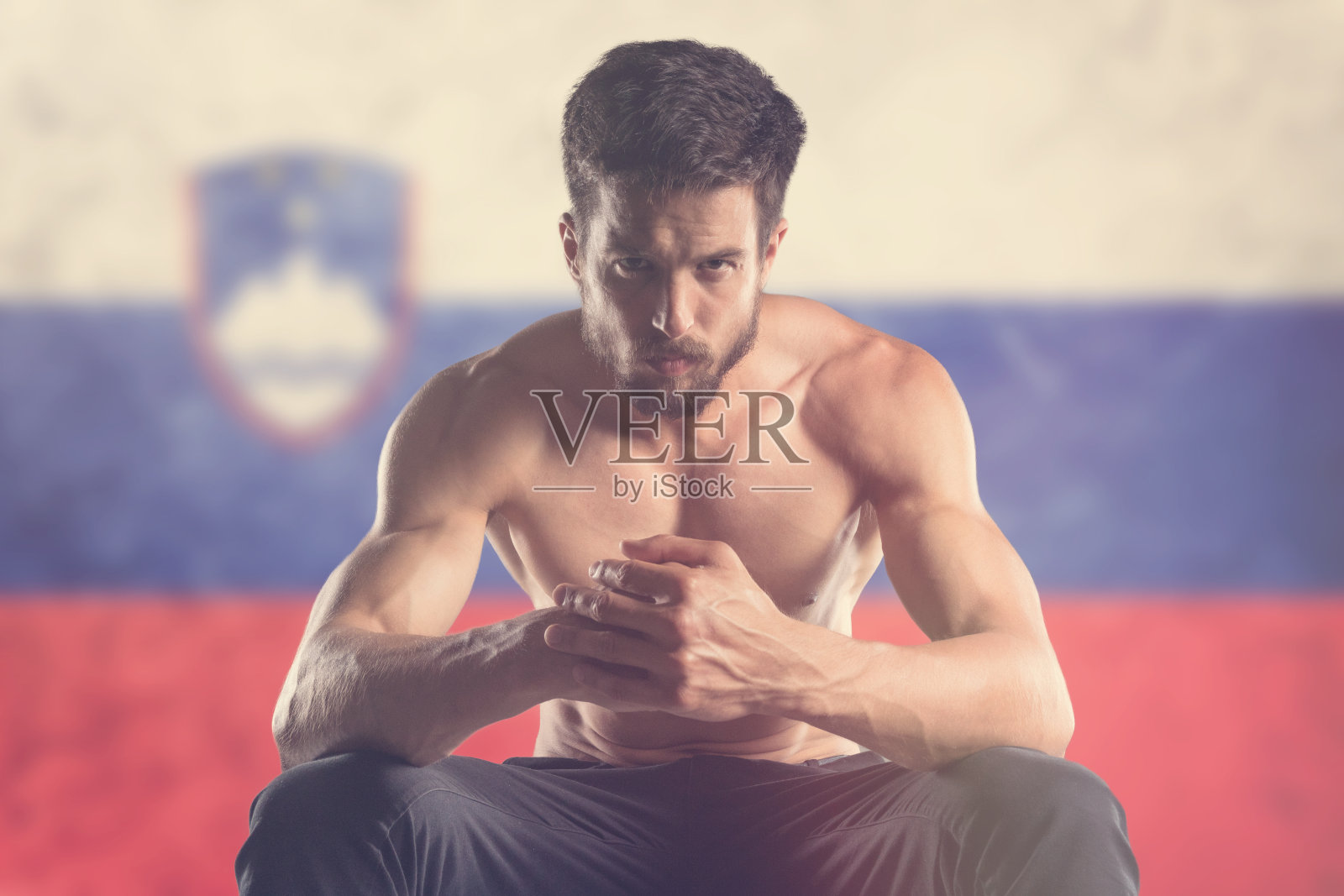 肌肉发达的男人，身后挂着斯洛文尼亚国旗照片摄影图片