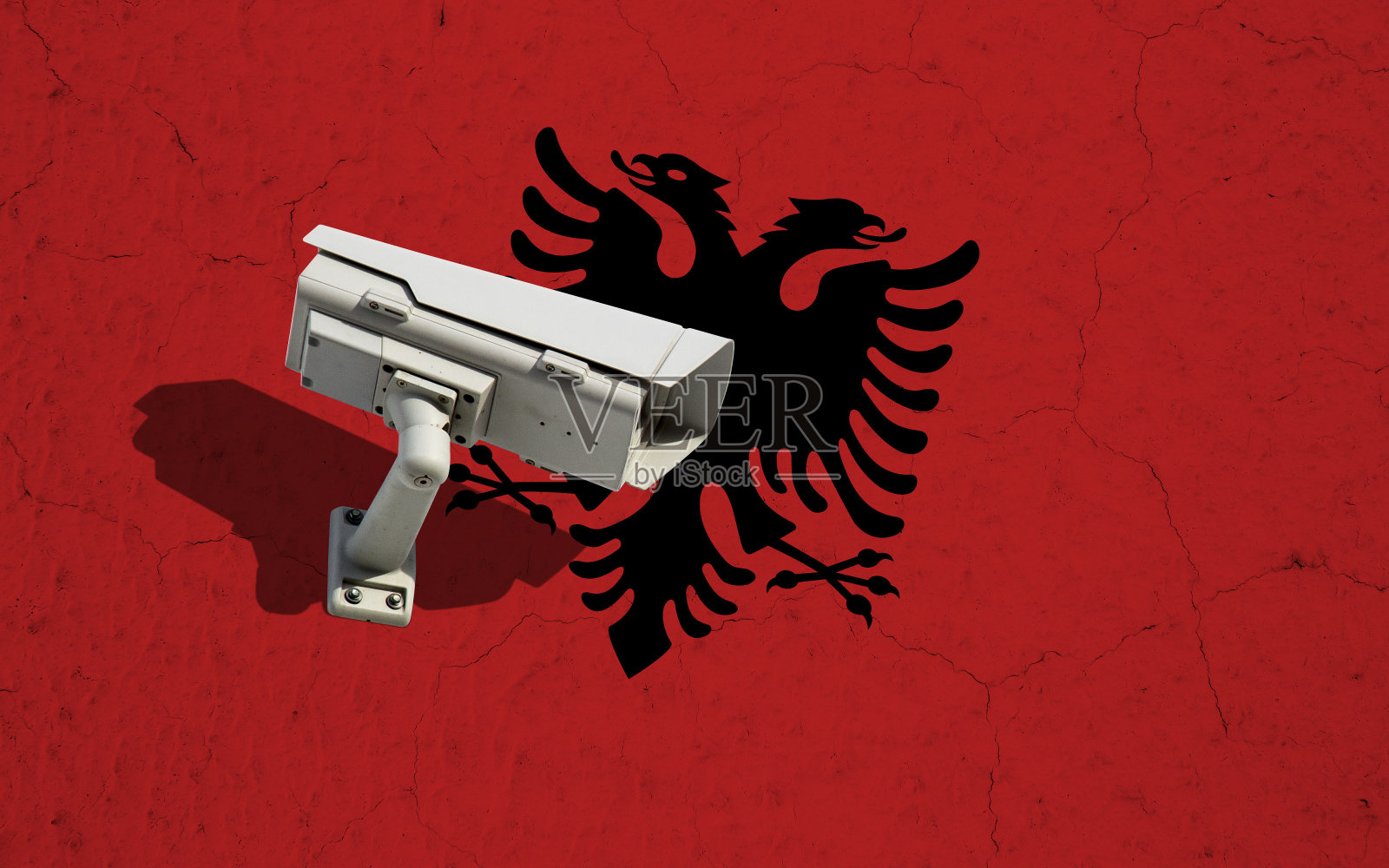 墙上挂着阿尔巴尼亚国旗，有裂缝还有摄像头监控照片摄影图片