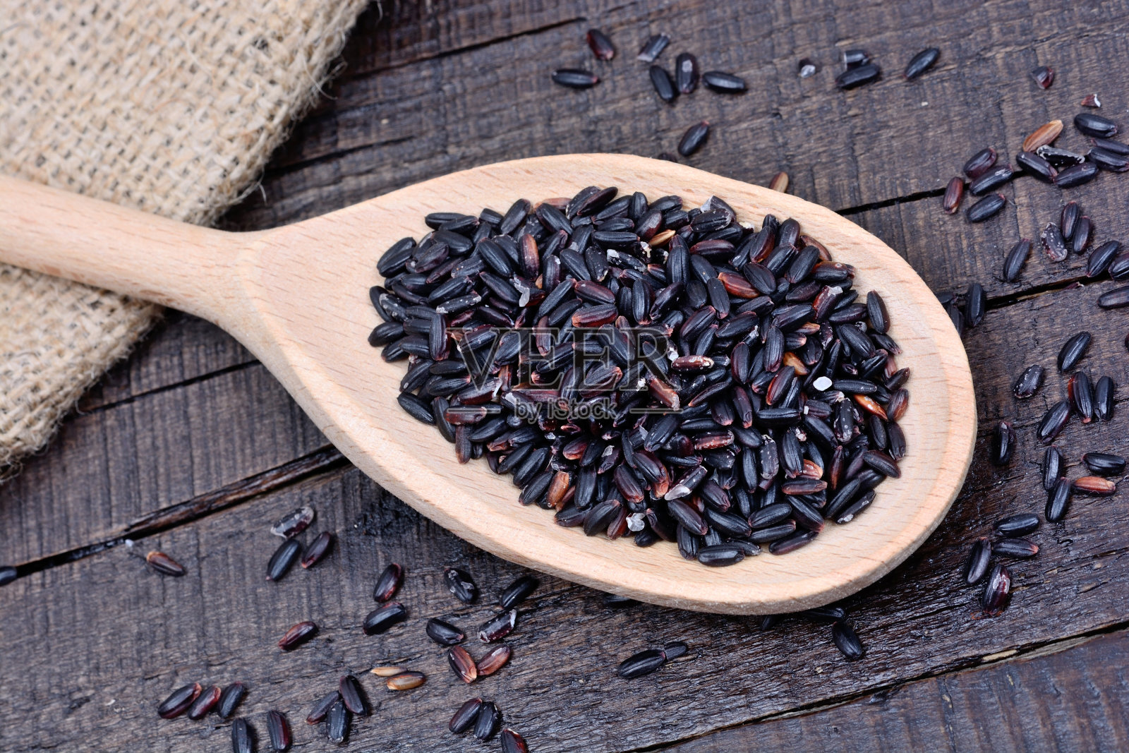 桌子上的木勺里盛着黑米照片摄影图片