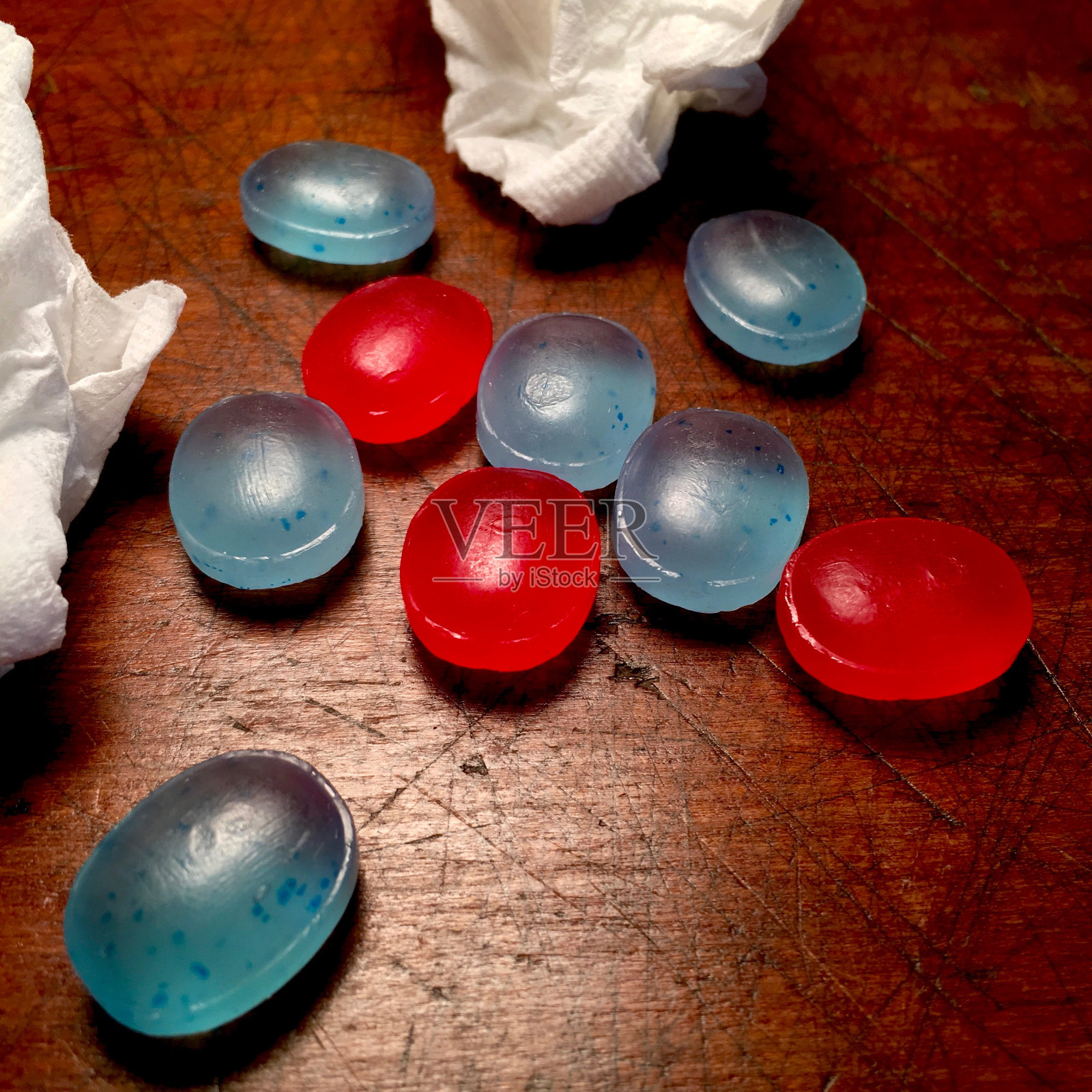 揉皱的纸巾和润喉糖在风化的木质背景上照片摄影图片