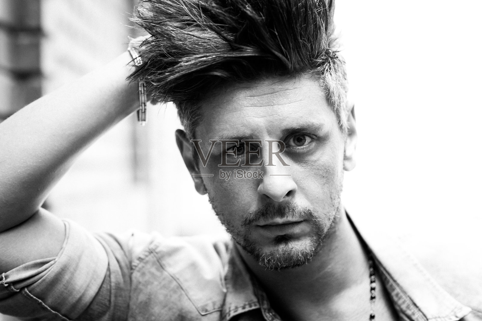 英俊男子的肖像靠在砖墙上，看向一边。黑白图像。城市人的概念。照片摄影图片