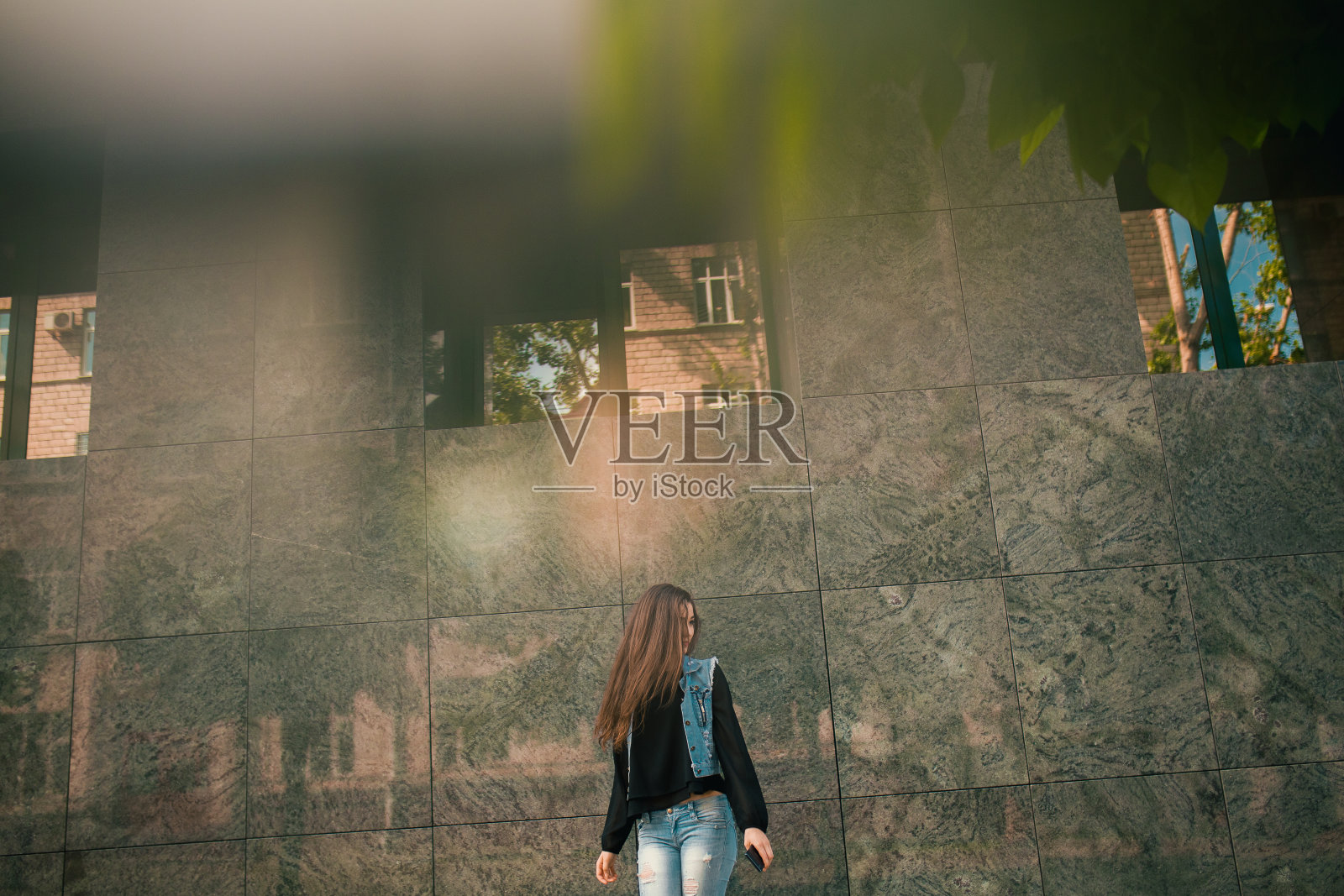 漂亮的青少年穿着牛仔裤和智能手机聊天，在城市里玩得很开心照片摄影图片