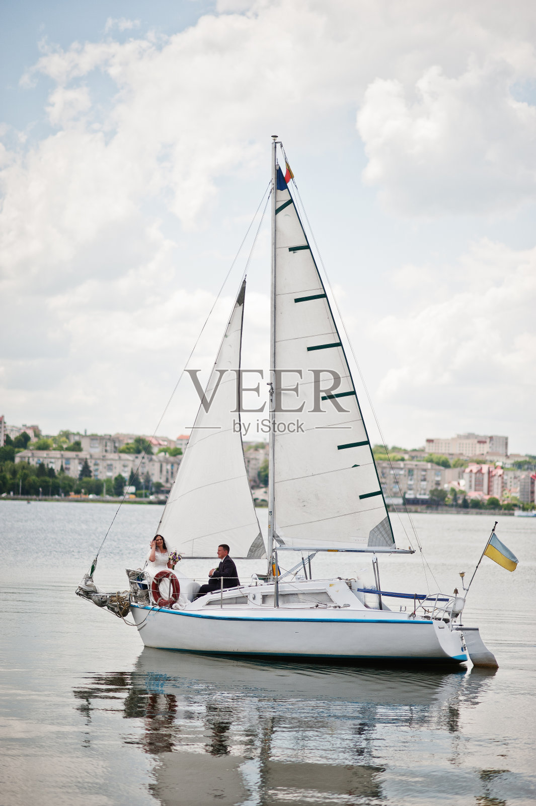 相爱的新婚夫妇在湖上的小帆船上。照片摄影图片