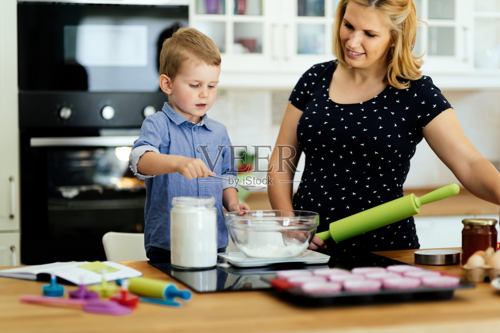 在现代化的厨房里，孩子帮妈妈做饼干照片摄影图片