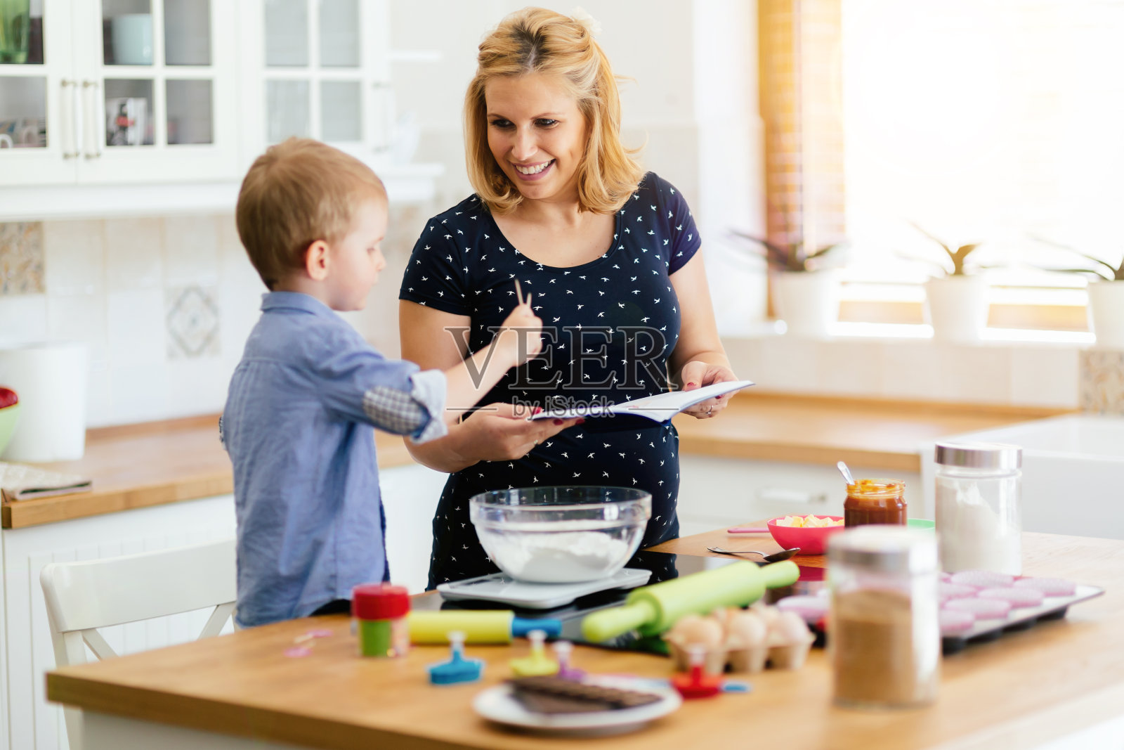 在现代化的厨房里，孩子帮妈妈做饼干照片摄影图片