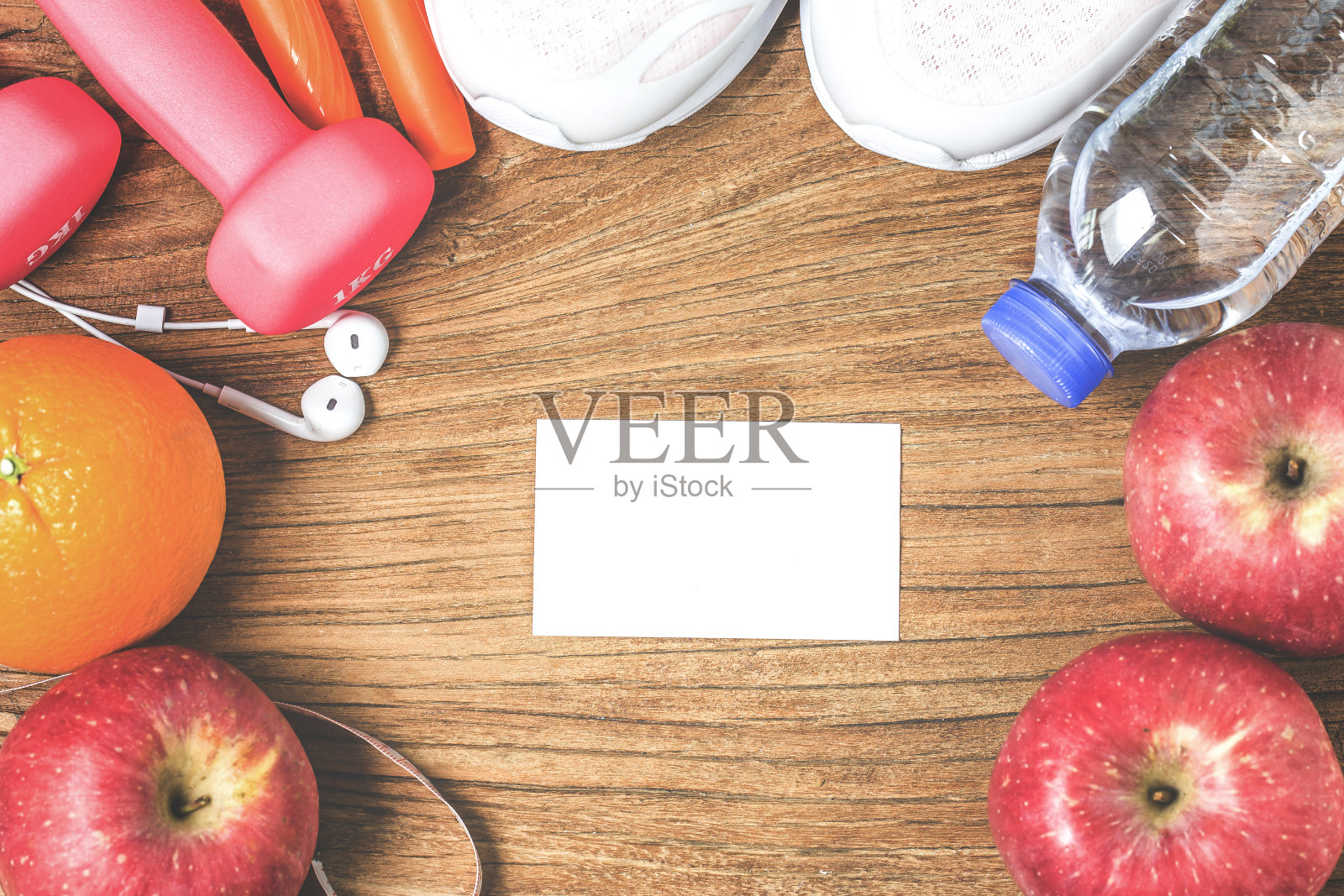 健身、健康和积极的生活方式概念，一瓶水，哑铃，运动鞋，带耳机的智能手机和木头背景上的苹果。为文本复制空间。俯视图照片摄影图片