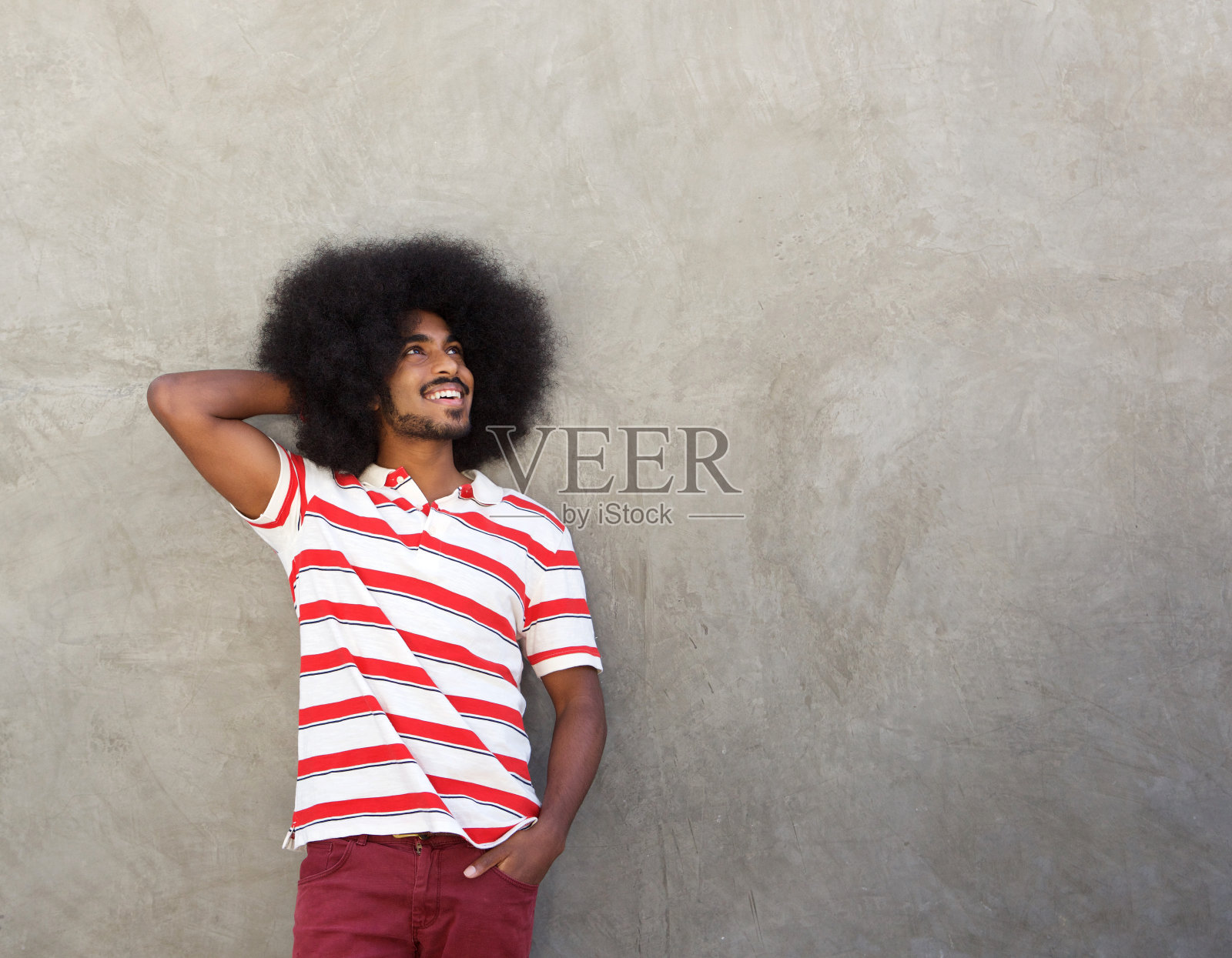 有魅力的男人站在墙边，手握头发微笑着照片摄影图片