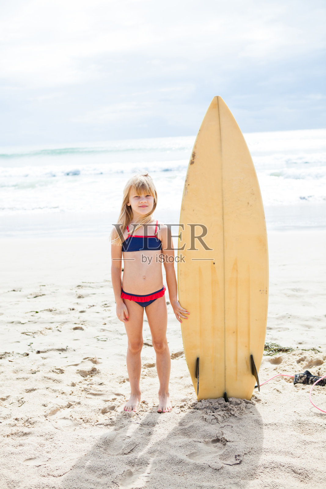 年轻的女孩和冲浪板站在海滩上照片摄影图片