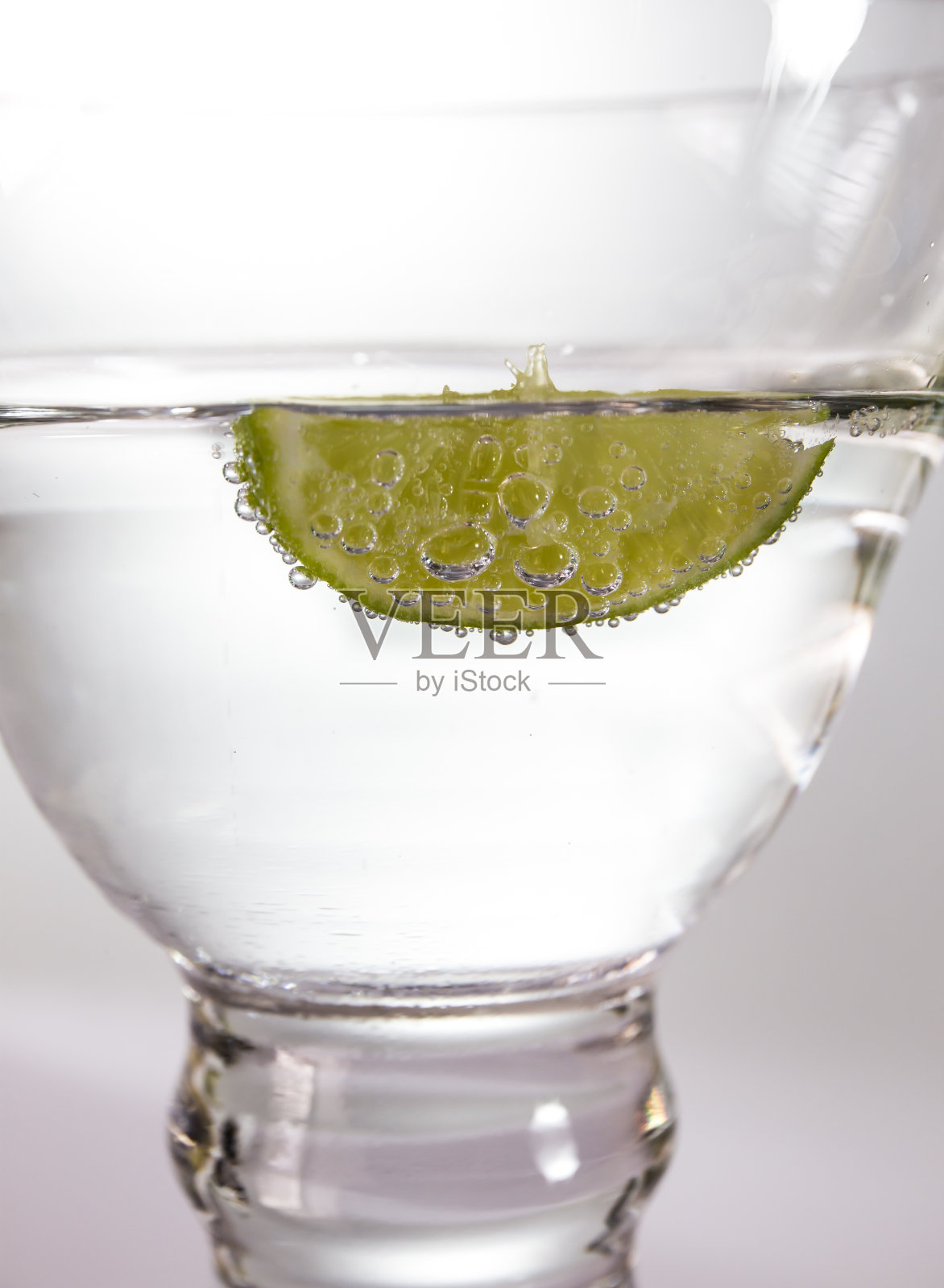 透明玻璃杯里的柠檬泡沫漂浮在水面上照片摄影图片