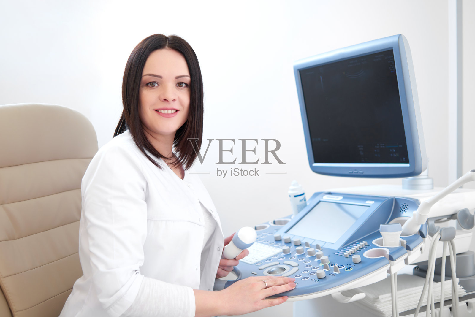 微笑医生使用超声波设备和电脑。照片摄影图片