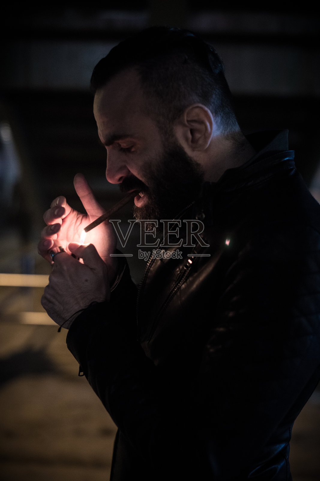 一名蓄着胡须的白人男子在纽约布鲁克林的街道上点燃一支香烟照片摄影图片