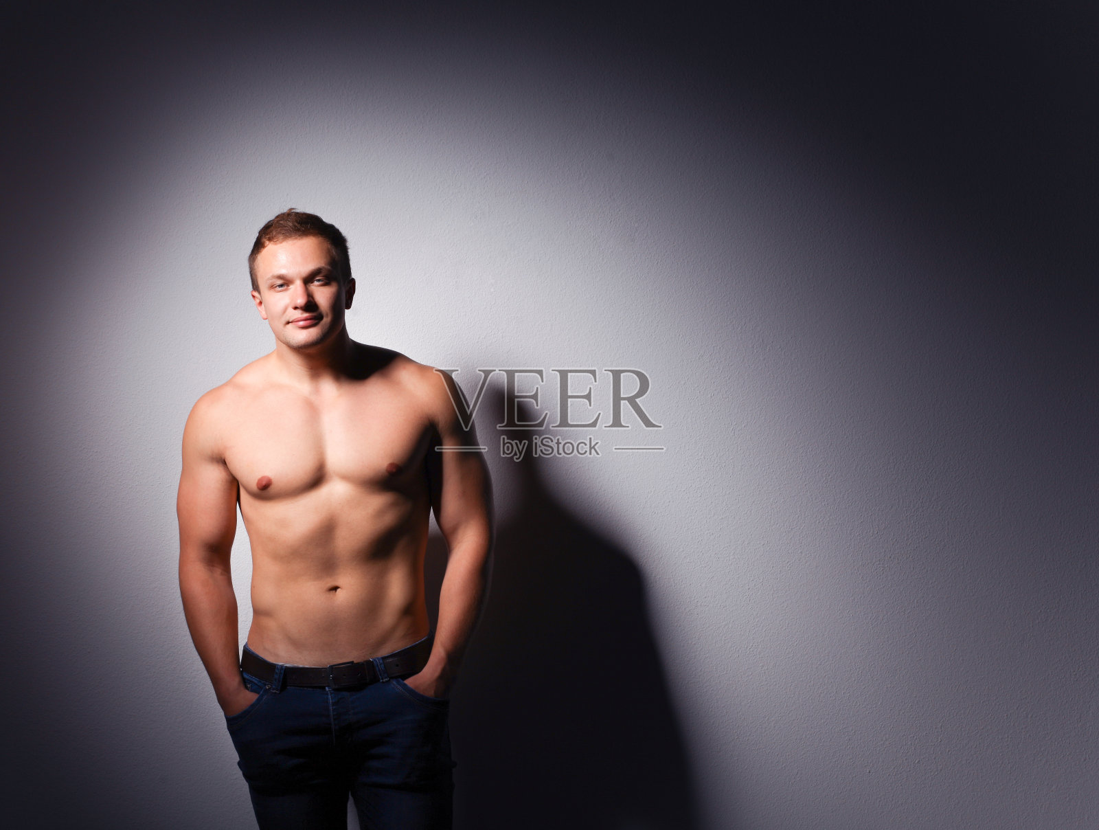 一个健康强壮的年轻人站在黑暗的背景上照片摄影图片