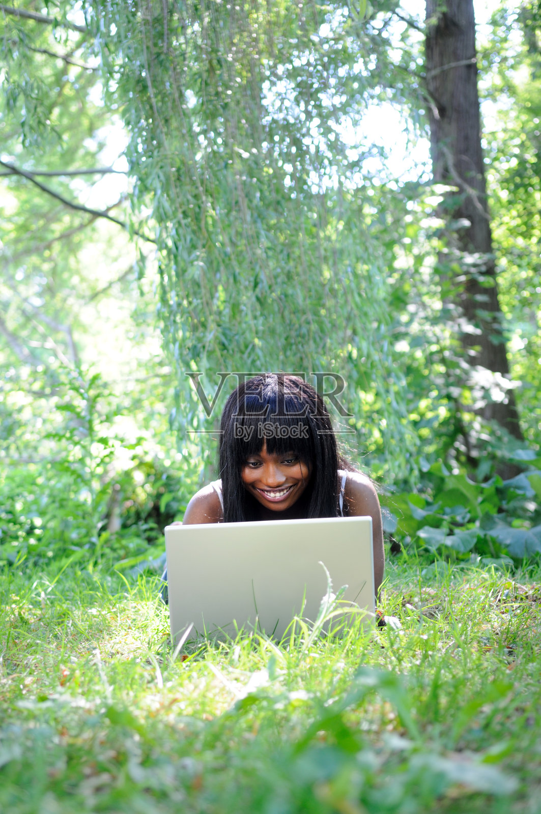 在公园里拿着笔记本电脑的美丽民族女人照片摄影图片