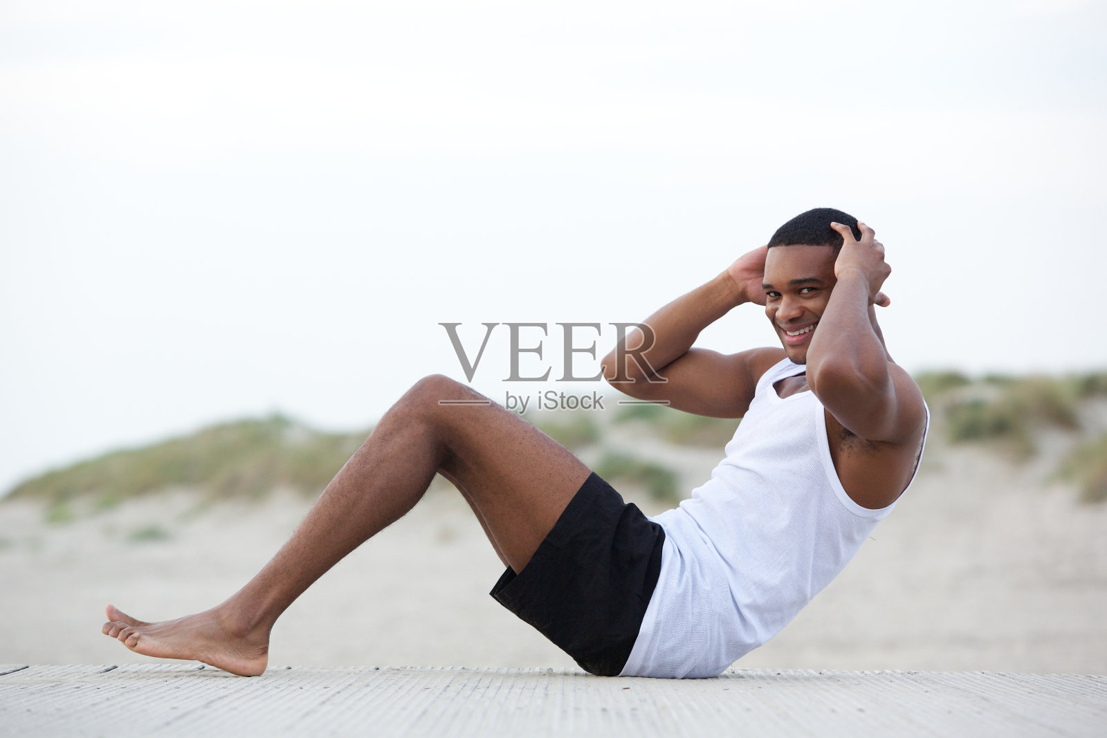 一个健康的年轻人在海滩上做仰卧起坐照片摄影图片