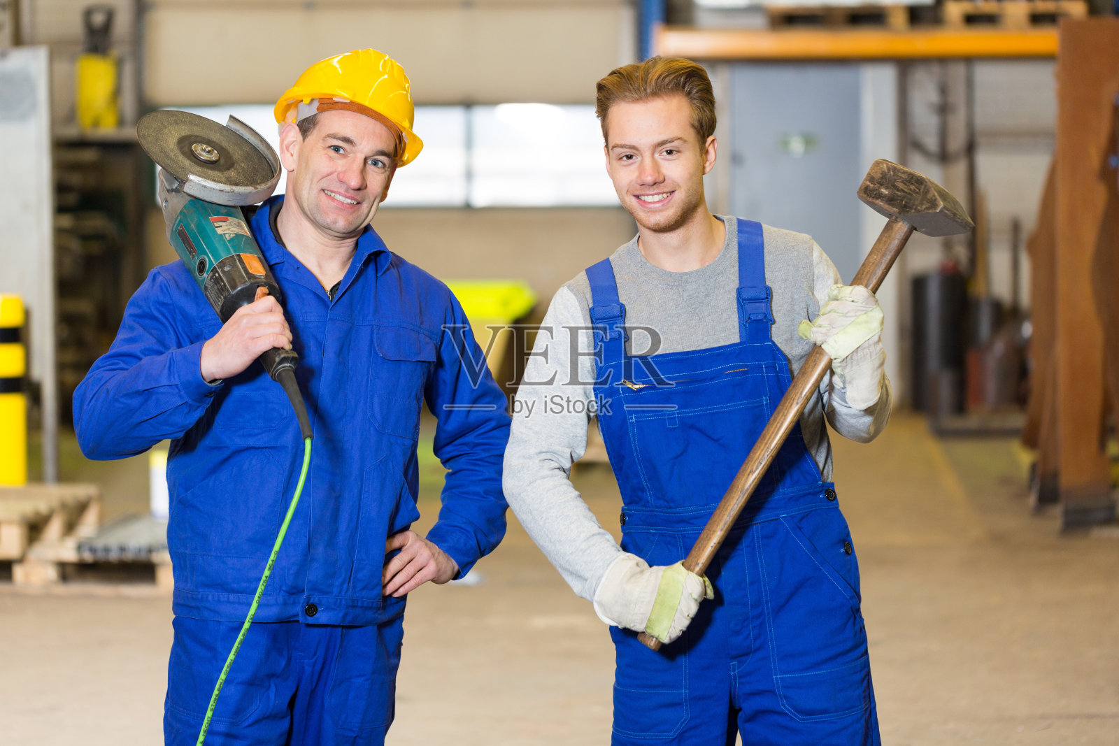 两名钢铁建筑工人与角磨床和火腿摆姿势照片摄影图片