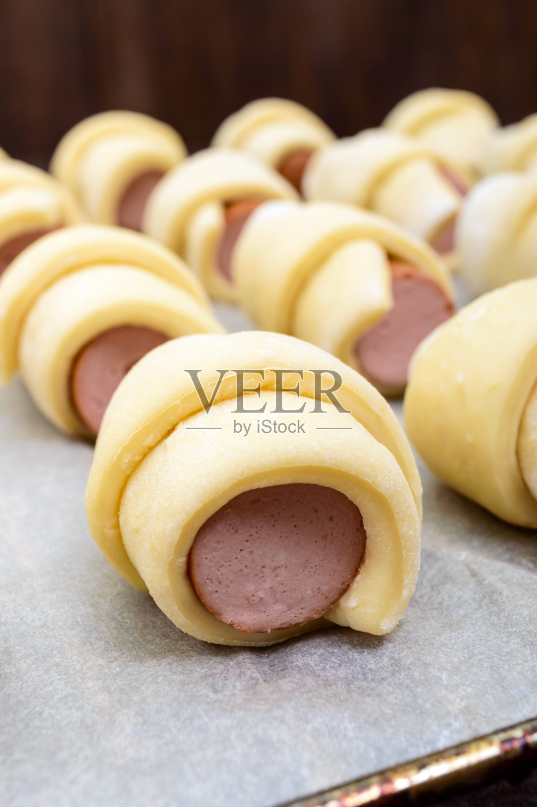 家庭烘焙:生面团中加入香肠。格子上有许多生面包照片摄影图片